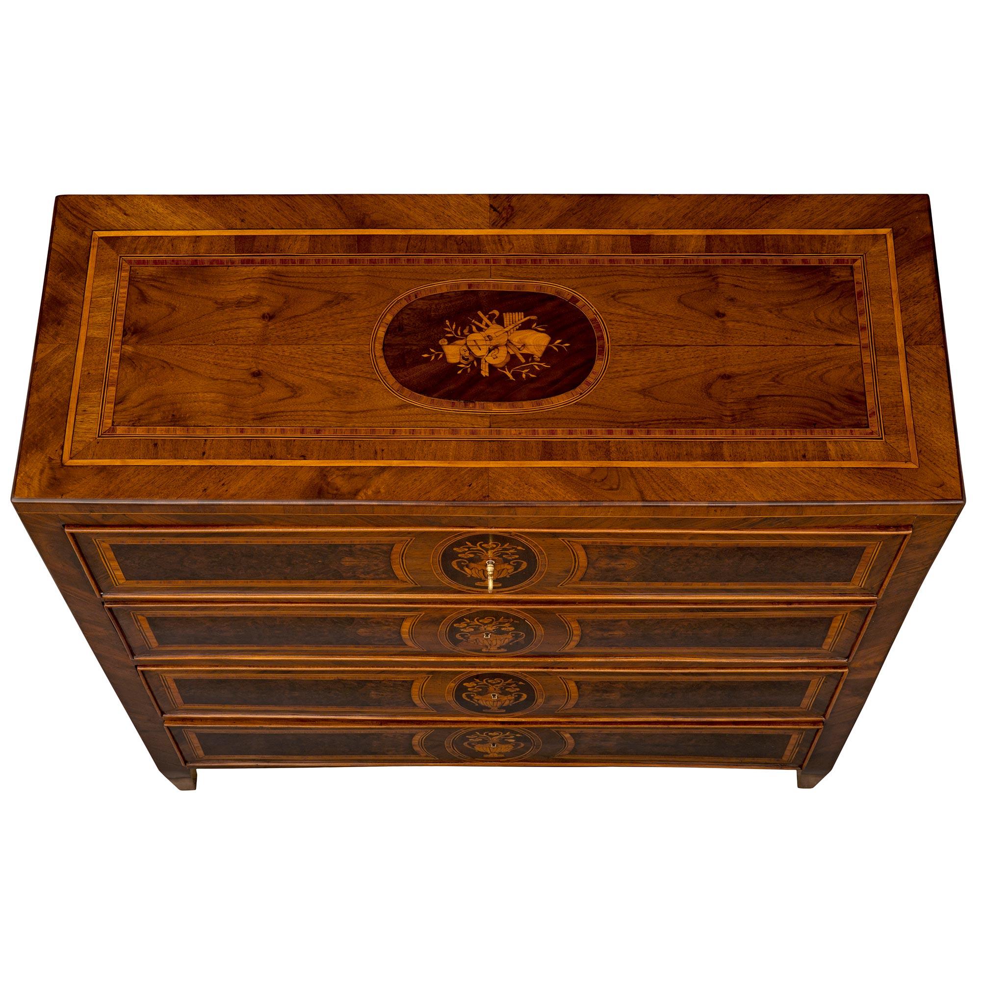 An elegant Italian 18th century Louis XVI period Walnut, Burl Walnut, and Tulipwood commode. The four door chest is raised by fine square tapered legs below the straight frieze. At the center are four drawers each decorated with an intricately