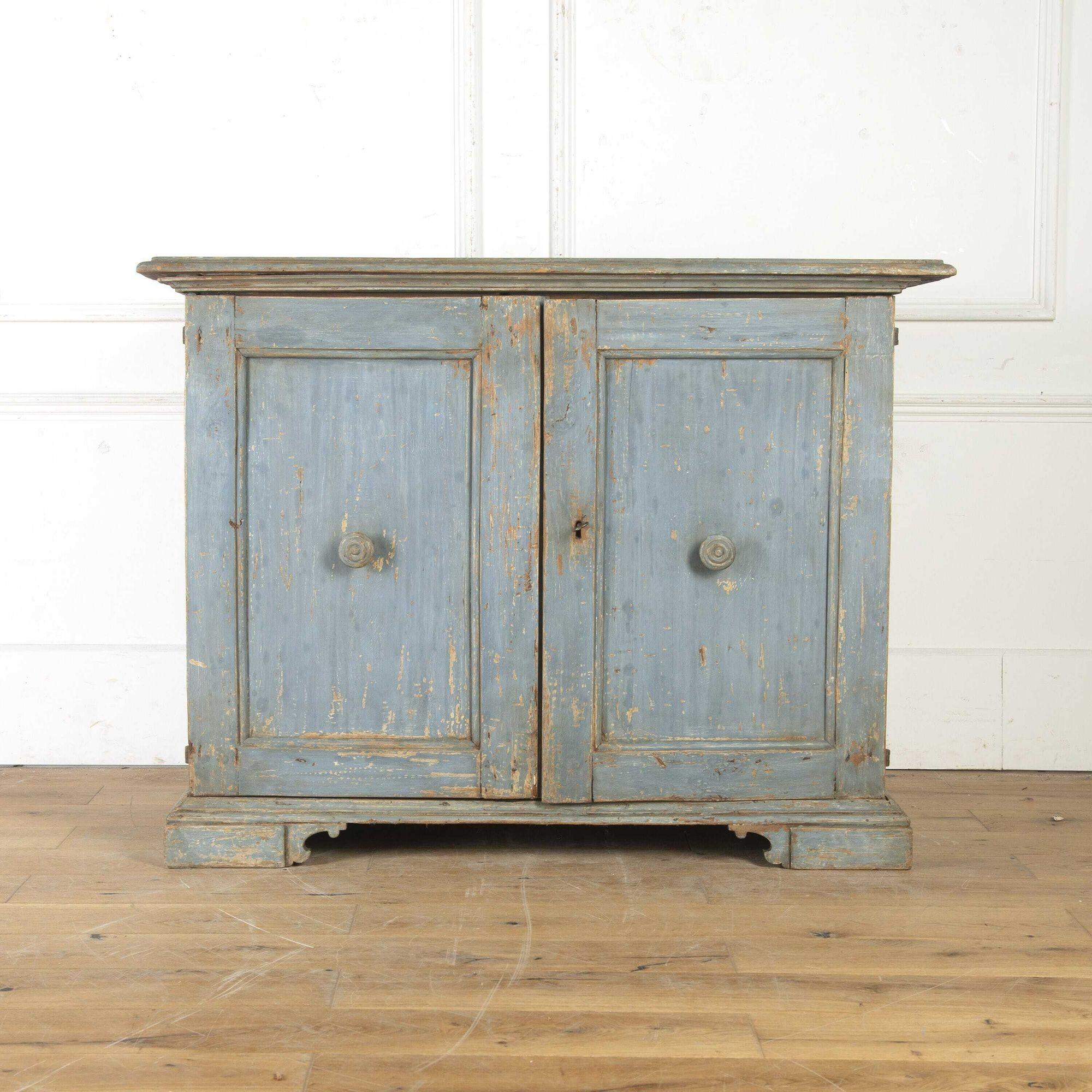Charming Italian 18th Century cupboard.
This cupboard has attractive low proportions, making it ideal for storage as well as display. 
The overhanging moulded top sits over two panelled doors with turned wooden handles.
The interior is a delightful