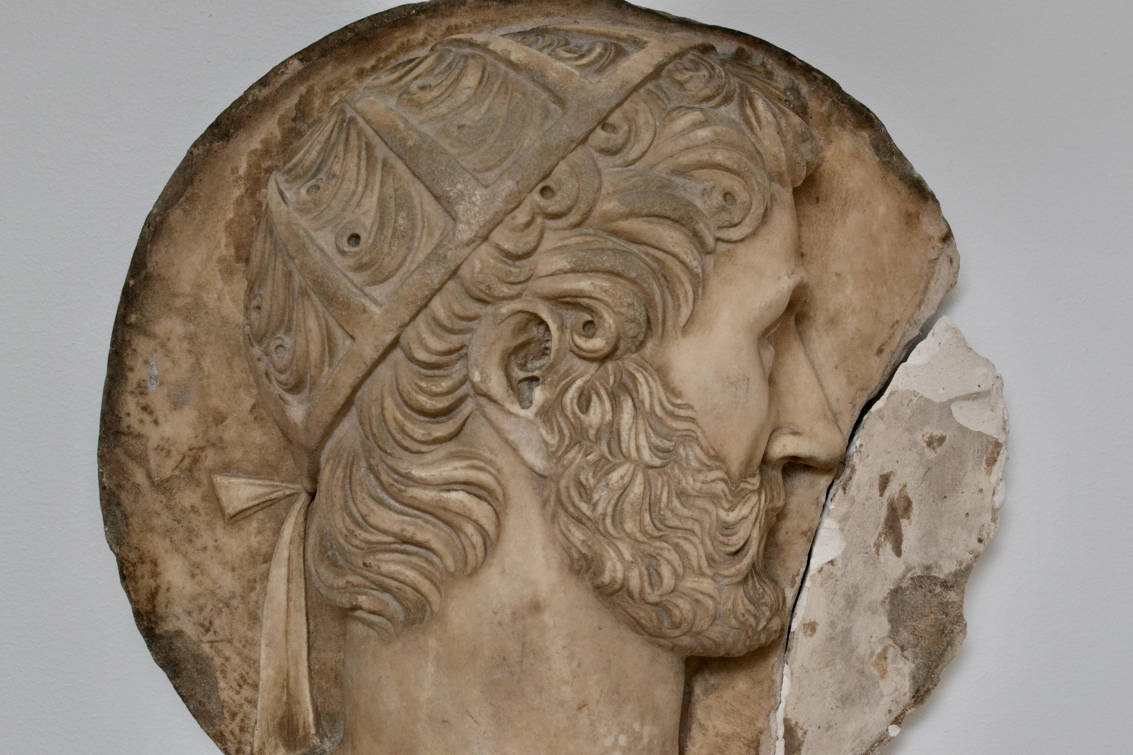 An 18th century Italian marble medallion portrait of a Greek/Roman dignitary wearing a head dress or hair net. The depicted head dress is quite unusual. This hand carved 