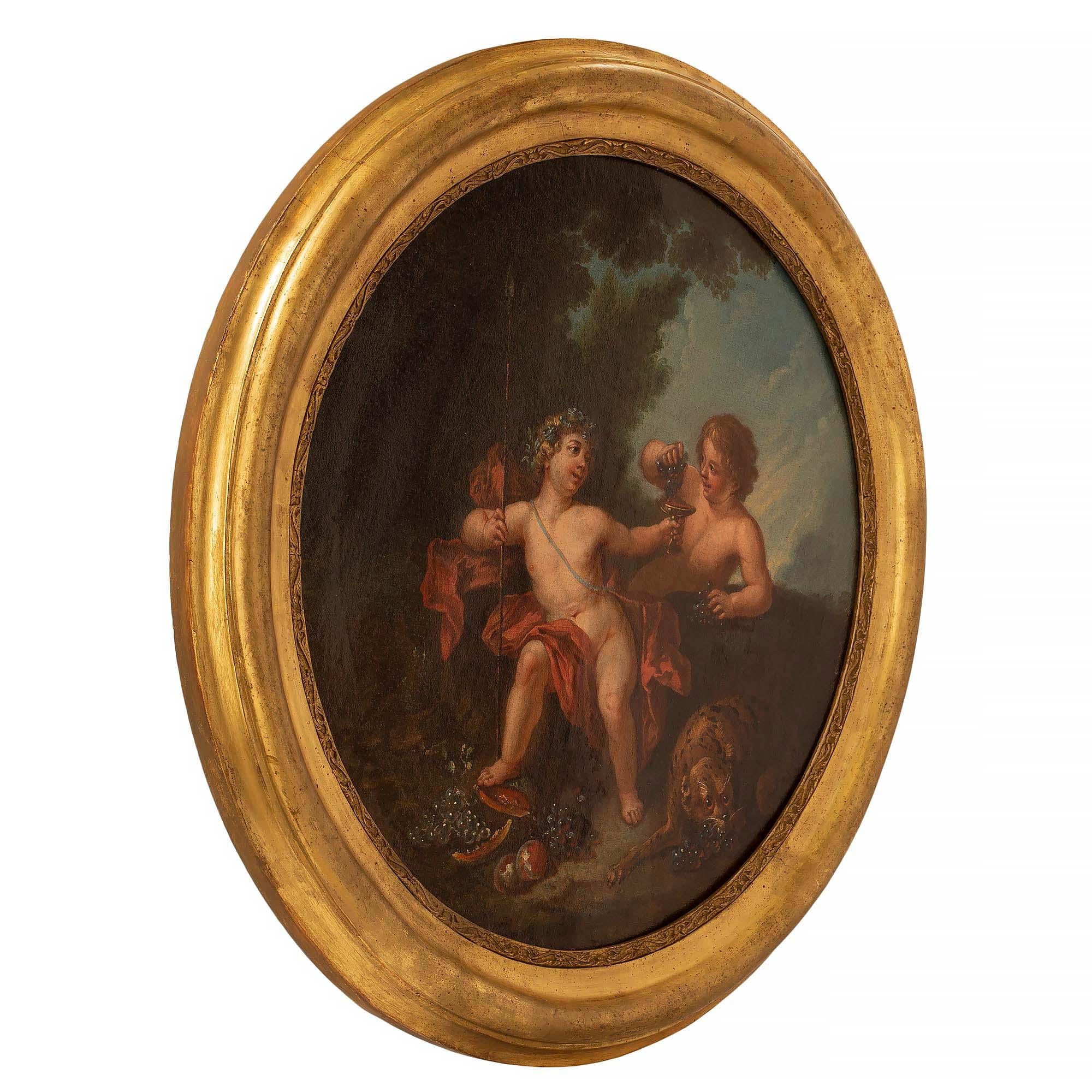 An extremely charming Italian 18th century Neo-Classical oil on canvas painting. The circular painting retains its original giltwood frame with a beautiful mottled designs and finely carved foliate border. The painting depicts two cherubs sitting