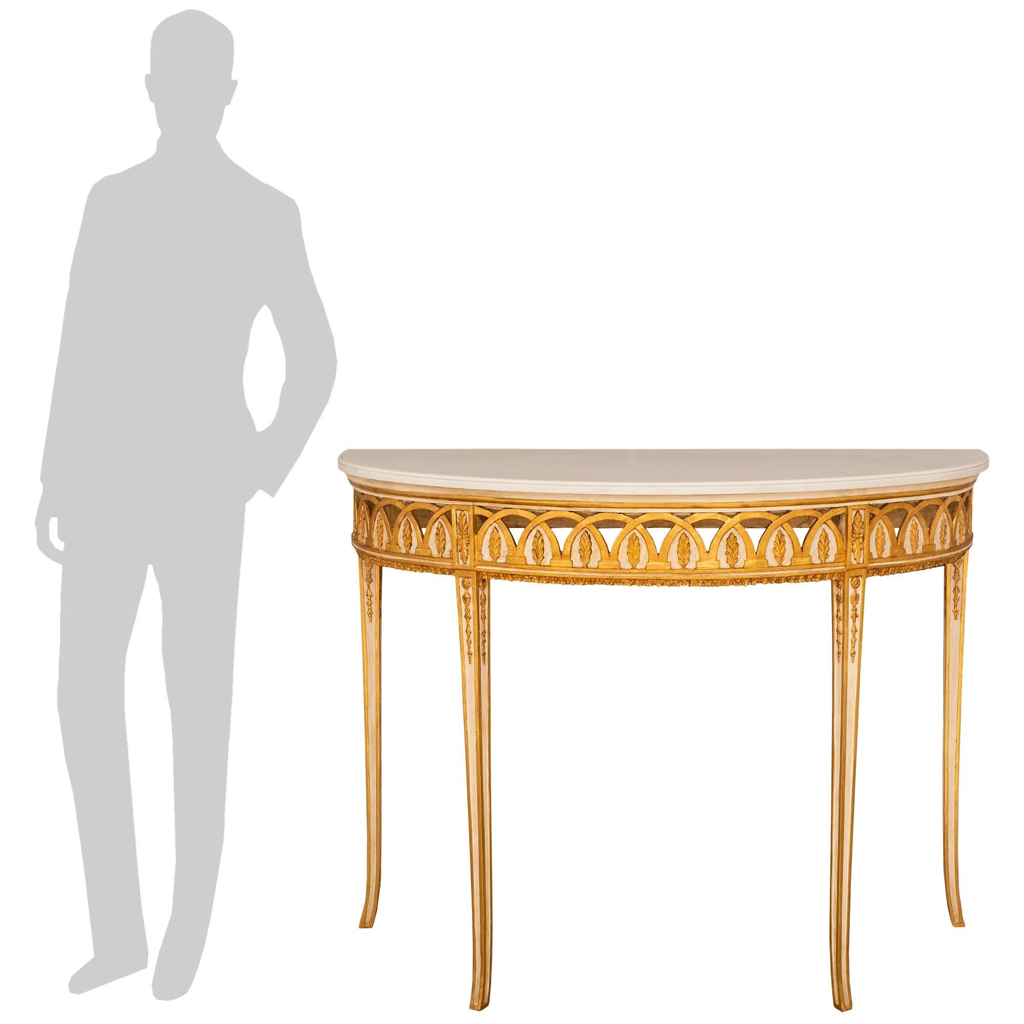 Un'elegante e attraente console neoclassica italiana del XVIII secolo, patinata in bianco sporco, in legno d'orato e marmo bianco di Carrara. Questa bellissima consolle freestanding a forma di demi-lune è sollevata da quattro gambe sottili,