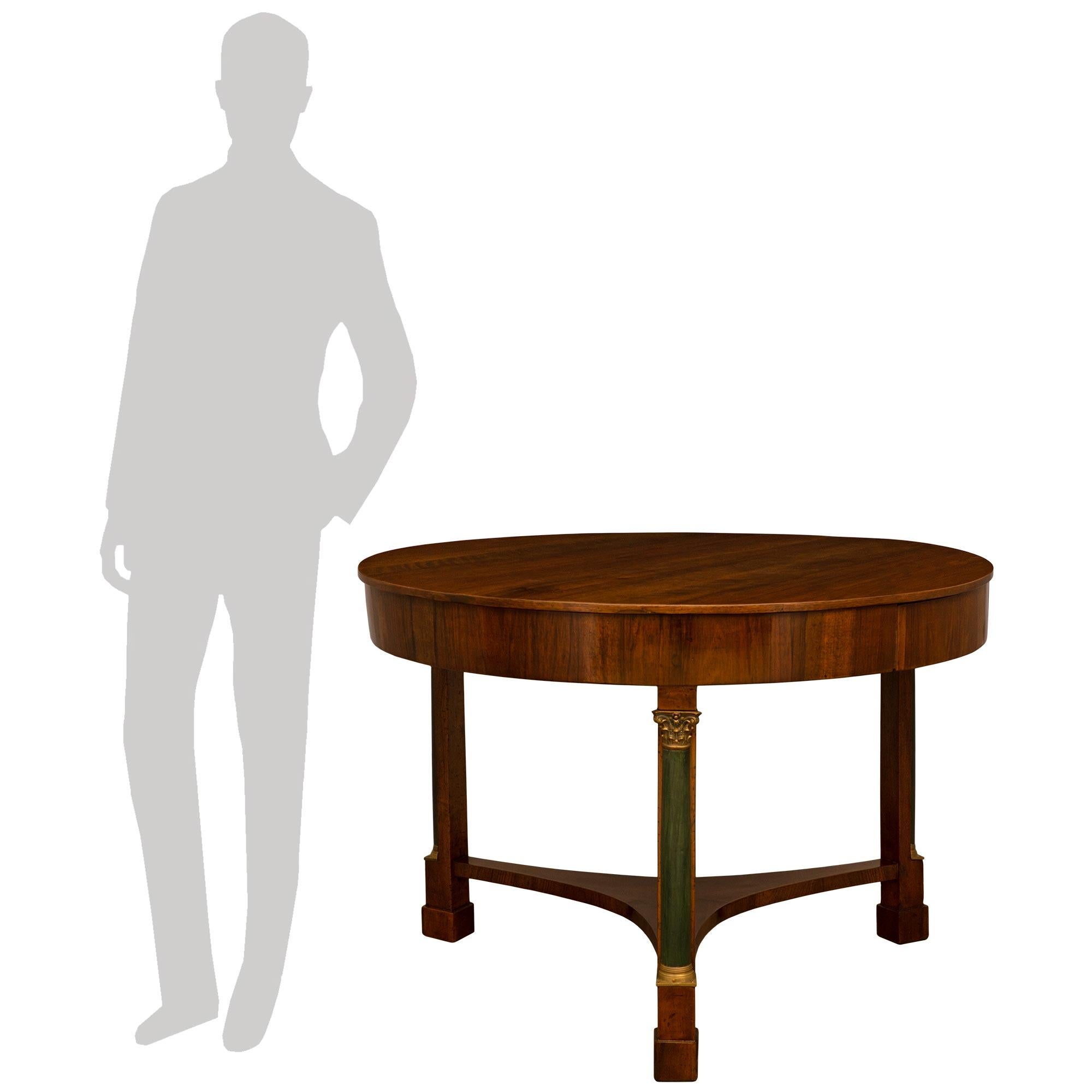 A handsome Italian 18th century neo-classical walnut center table with one drawer. The table is raised by three handsome square legs with an outstanding patinated column with a fine brass plinth and capital. Each leg is connected by an elegant
