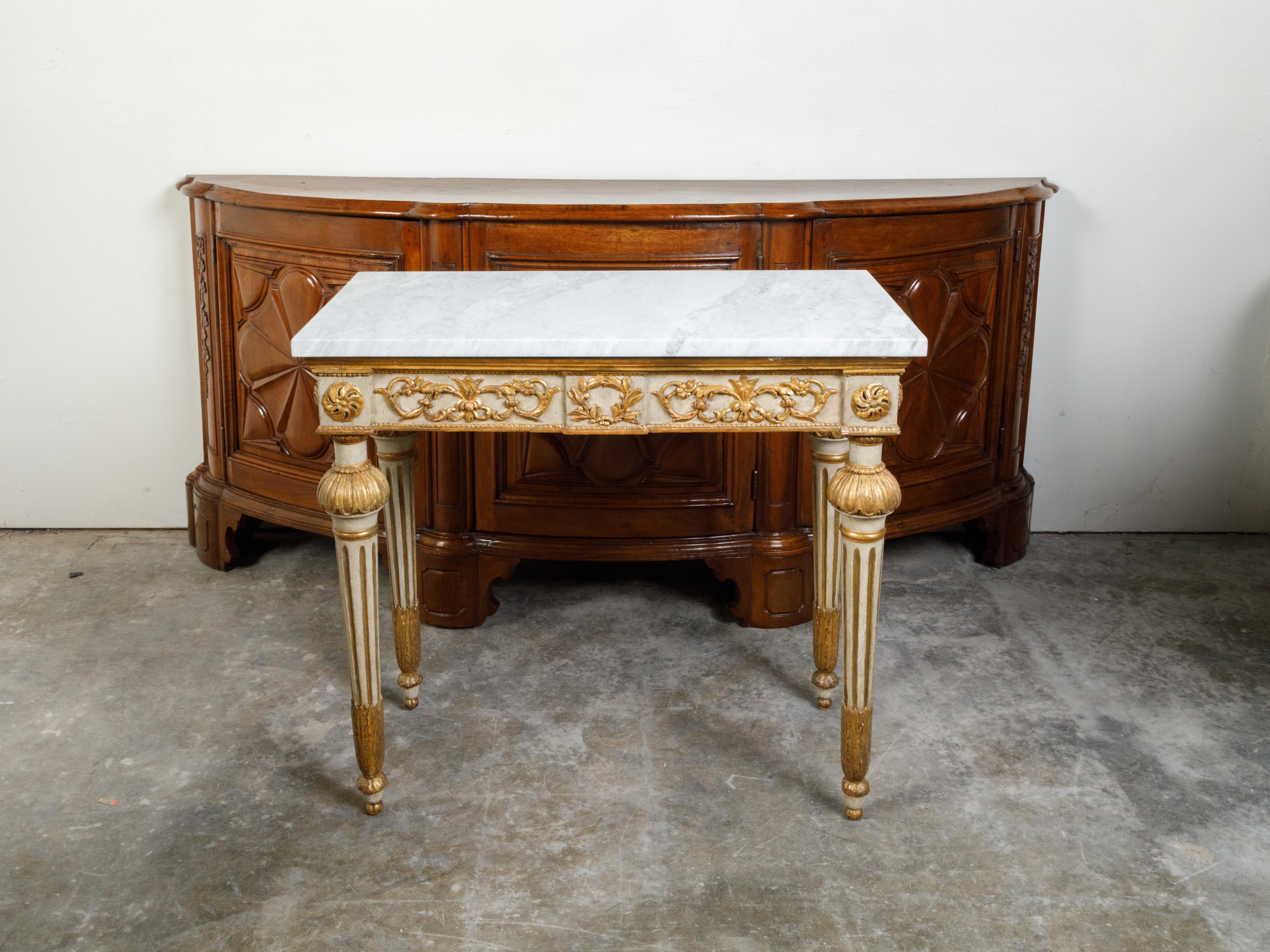 An Italian Neoclassical period painted and gilt console table from the 18th century, with white marble top and hand-carved décor. Created in Italy during the 18th century, this Neoclassical console table features a rectangular white marble top