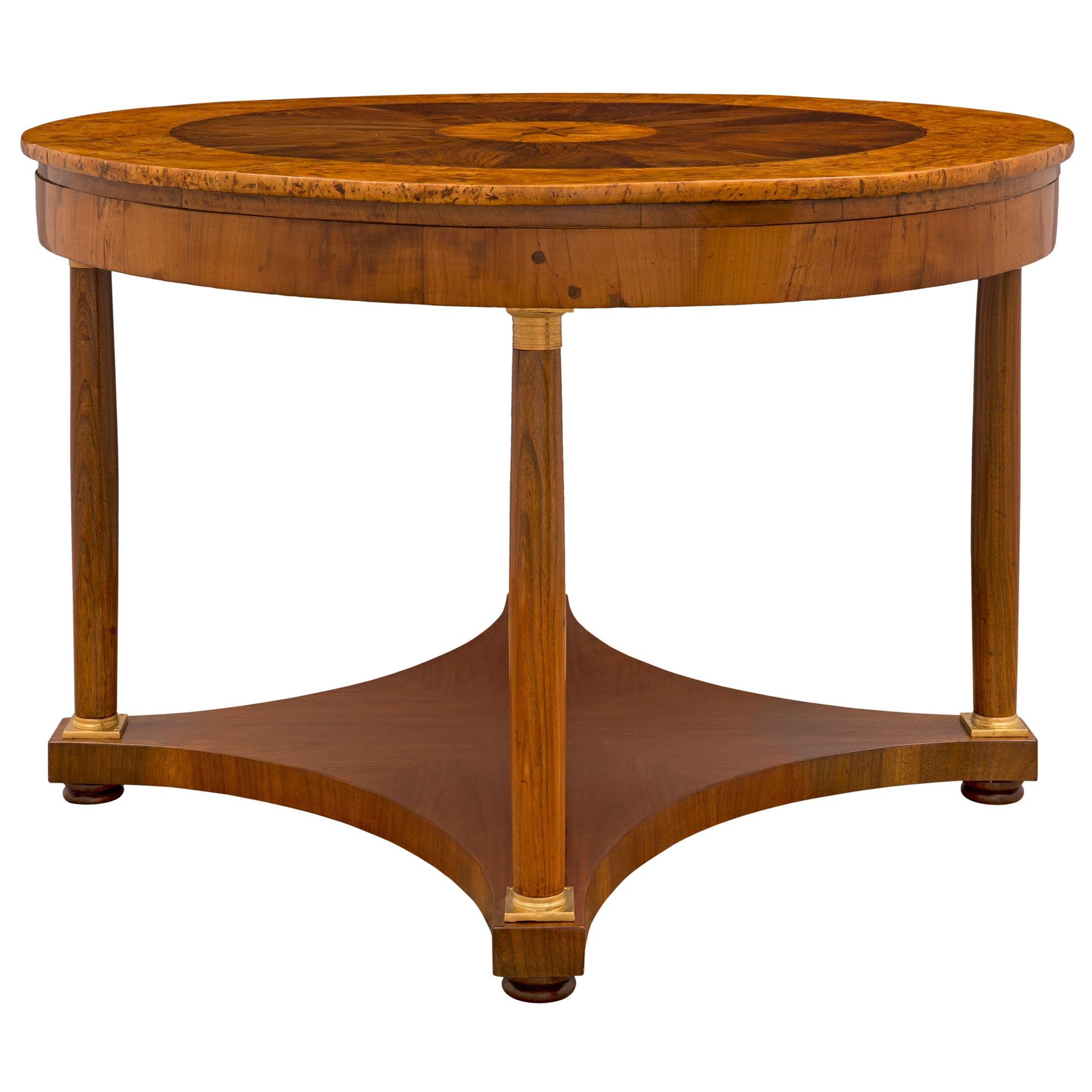 A striking and most decorative Italian 18th century Neo-Classical st. walnut, burl walnut, mahogany and ormolu center table. The circular table is raised by four beautiful circular column supports with fine ormolu top and bottom caps and charming