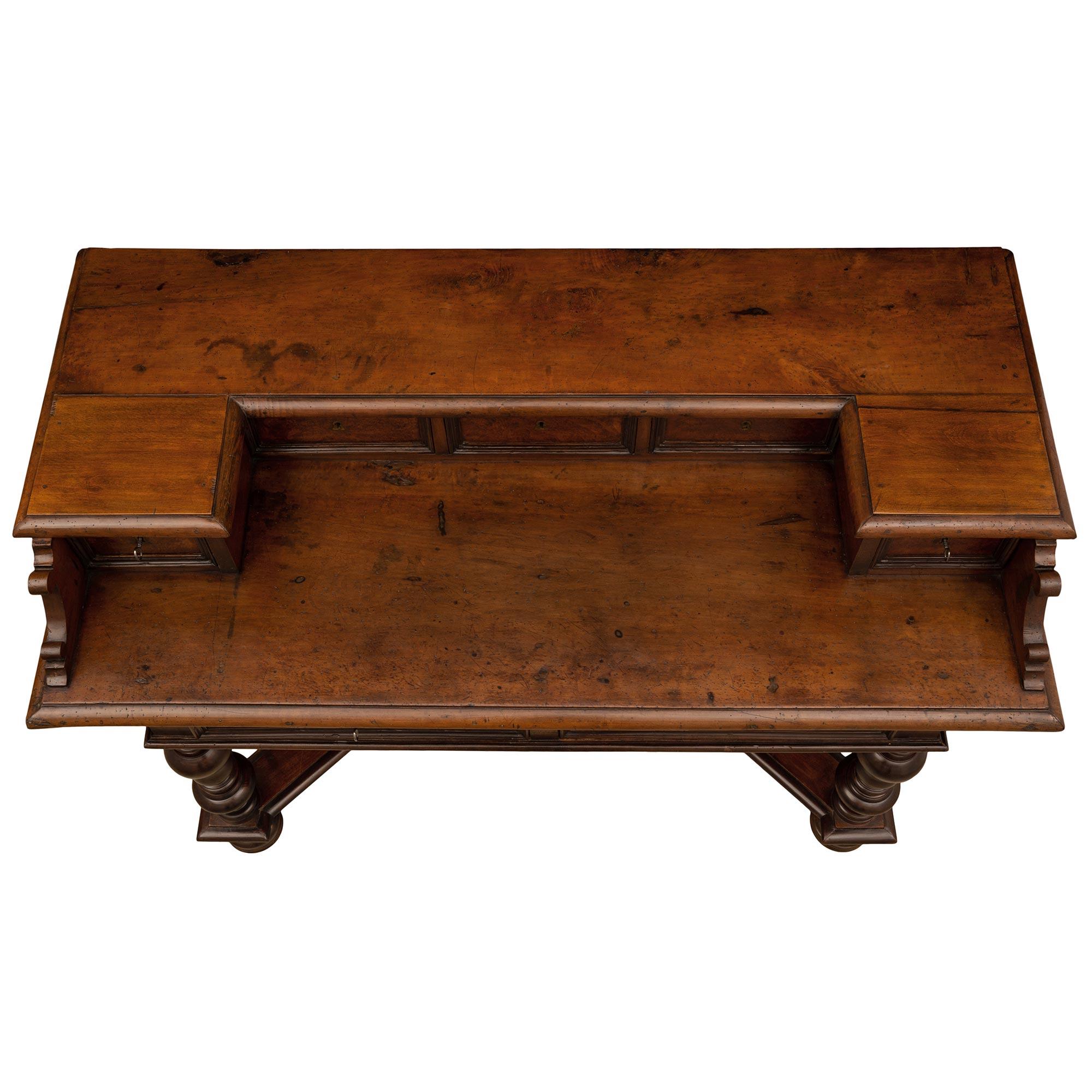 A most handsome Italian 18th-century walnut, burl walnut, and iron desk. The desk is raised by fine bun-shaped feet below impressive turned baluster-shaped legs each connected by an 'X' stretcher with a mottled border. The straight apron displays