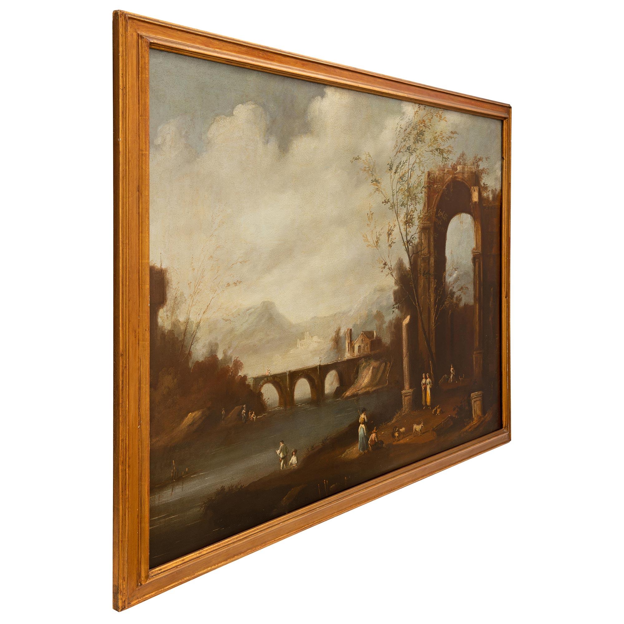 A beautiful large scale Italian 18th century oil on canvas painting in a giltwood frame. The painting depicts the lovely Italian countryside with charming personages dressed in classical country attire in the foreground feeding goats at the foot of