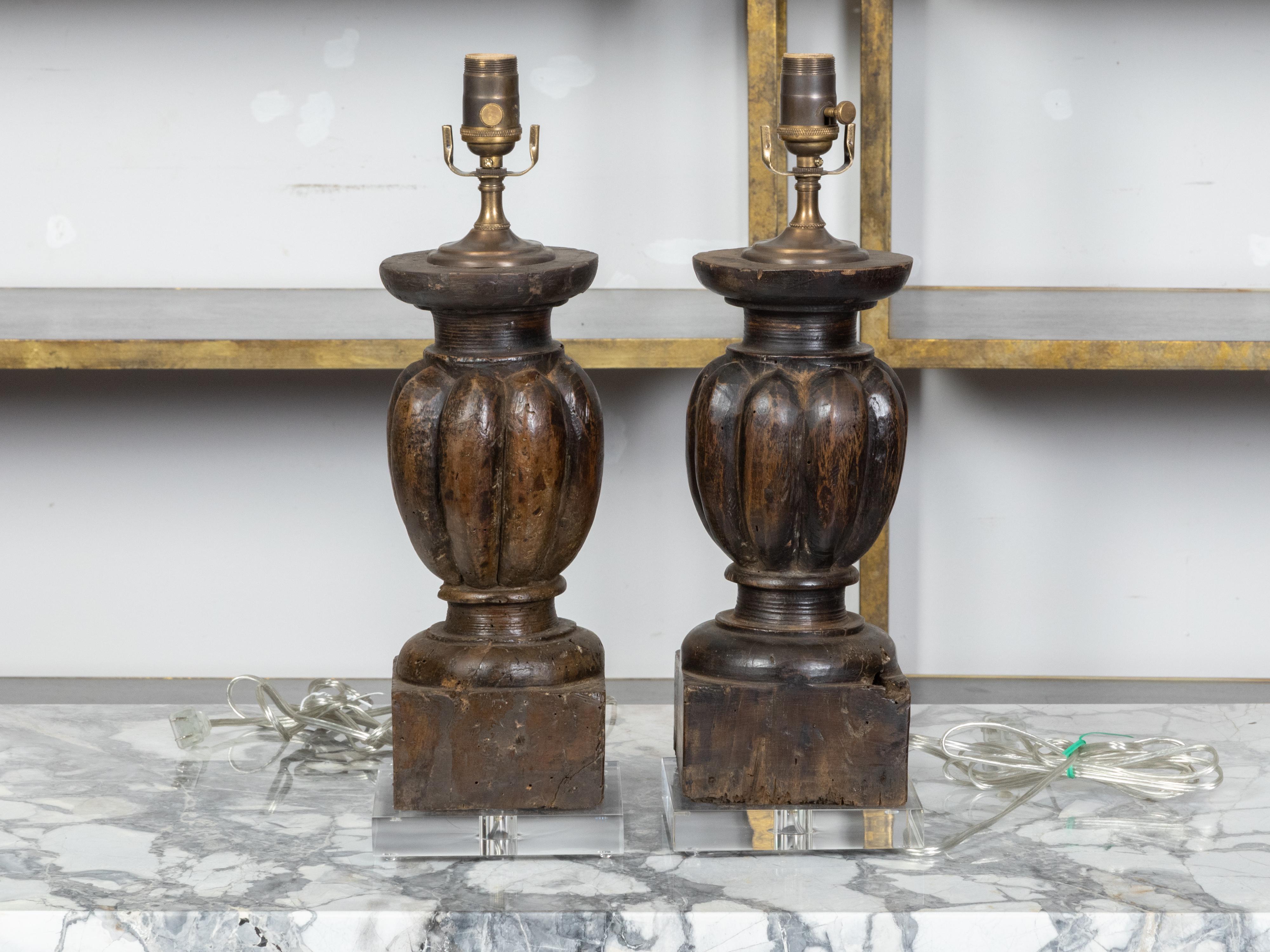 A pair of Italian carved wooden fragments from the 18th century depicting balusters with gadroon motifs, made into US wired table lamps mounted on square lucite bases. Created in Italy during the later years of the 18th century, each of this pair of