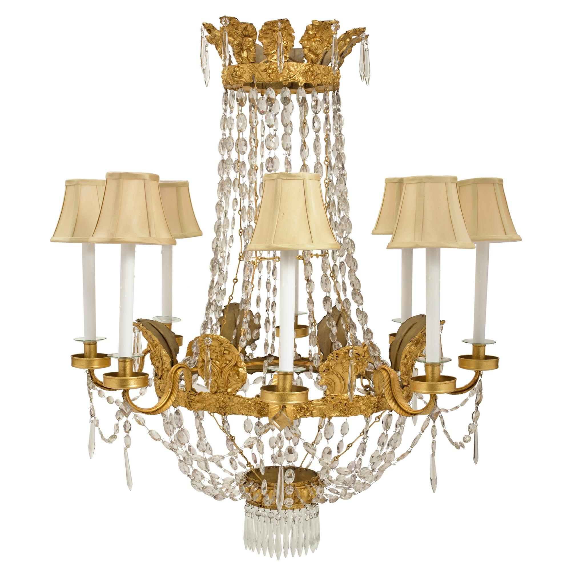 A very decorative Italian 18th century pressed gilt metal and crystal eight light chandelier. At the bottom is a lovely gilt metal Les Oves designed base with hanging pendants. Crystal garlands join to the central gilt metal band with foliate