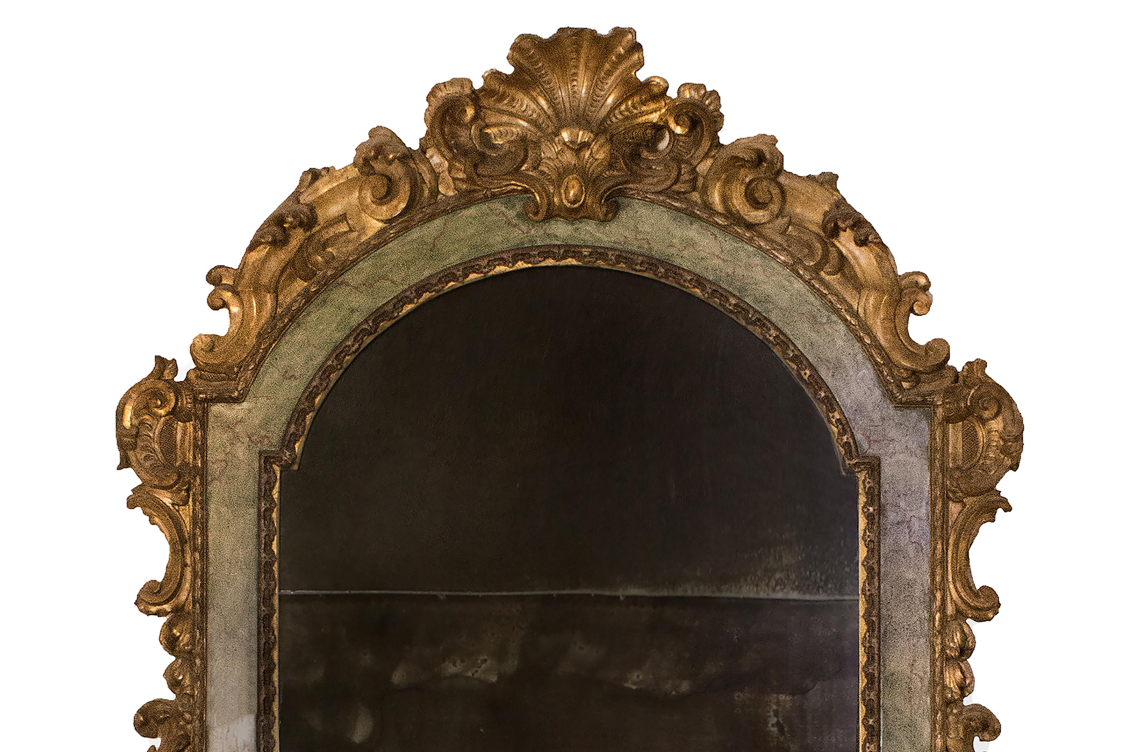 Italian 18th century Rococo archtop painted and gilded mirror. The frame is decorated with gold leaf c-scroll leaves and urns with a shell sculpted and carved molding. It has marbleized painted inlay with muted colors of blue, green, and gray with