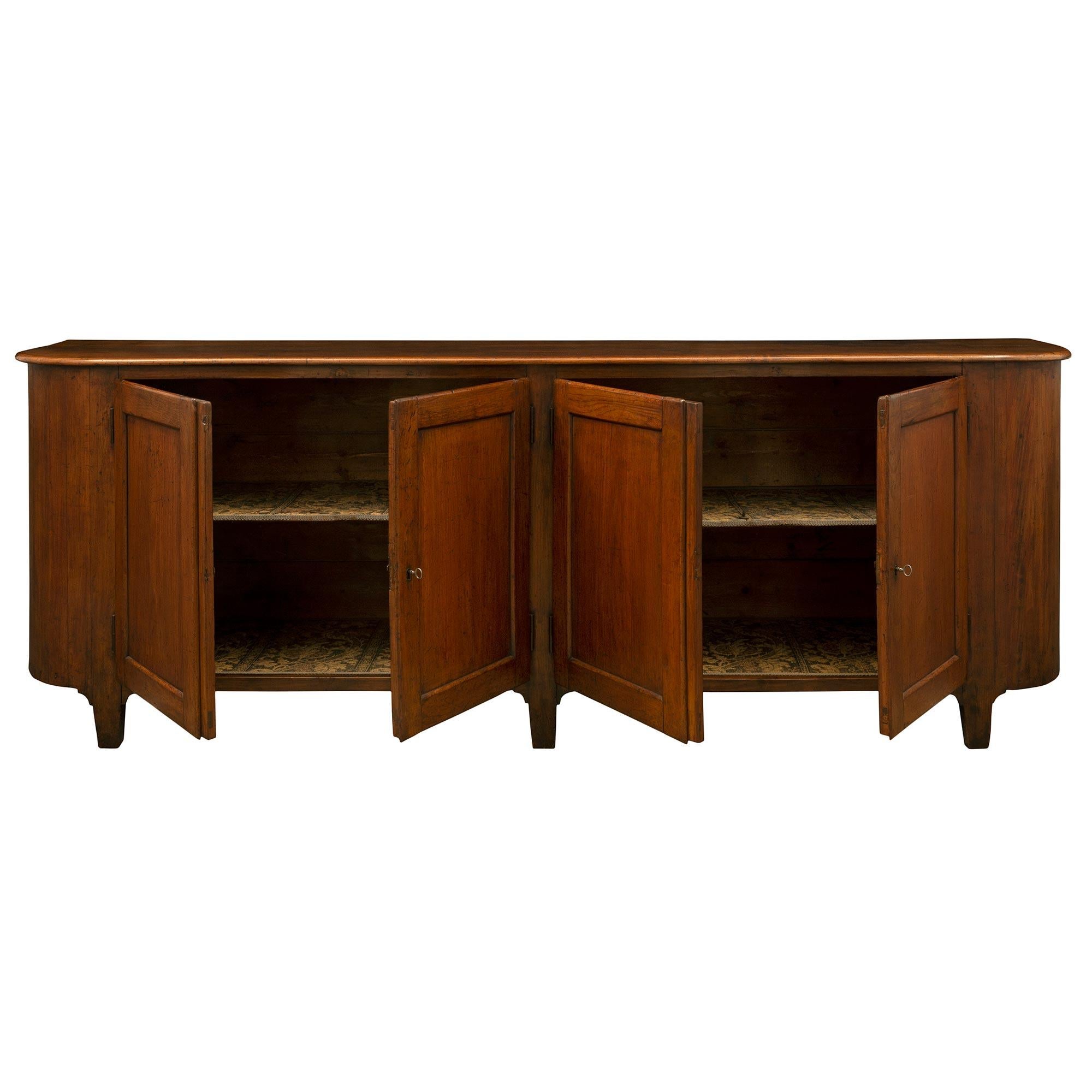 A handsome and very large scale Italian 18th century solid Walnut country buffet from Tuscany. The four door buffet is raised by five elegant rectangular tapered legs below the straight frieze and rounded sides. At the front are two pairs of doors