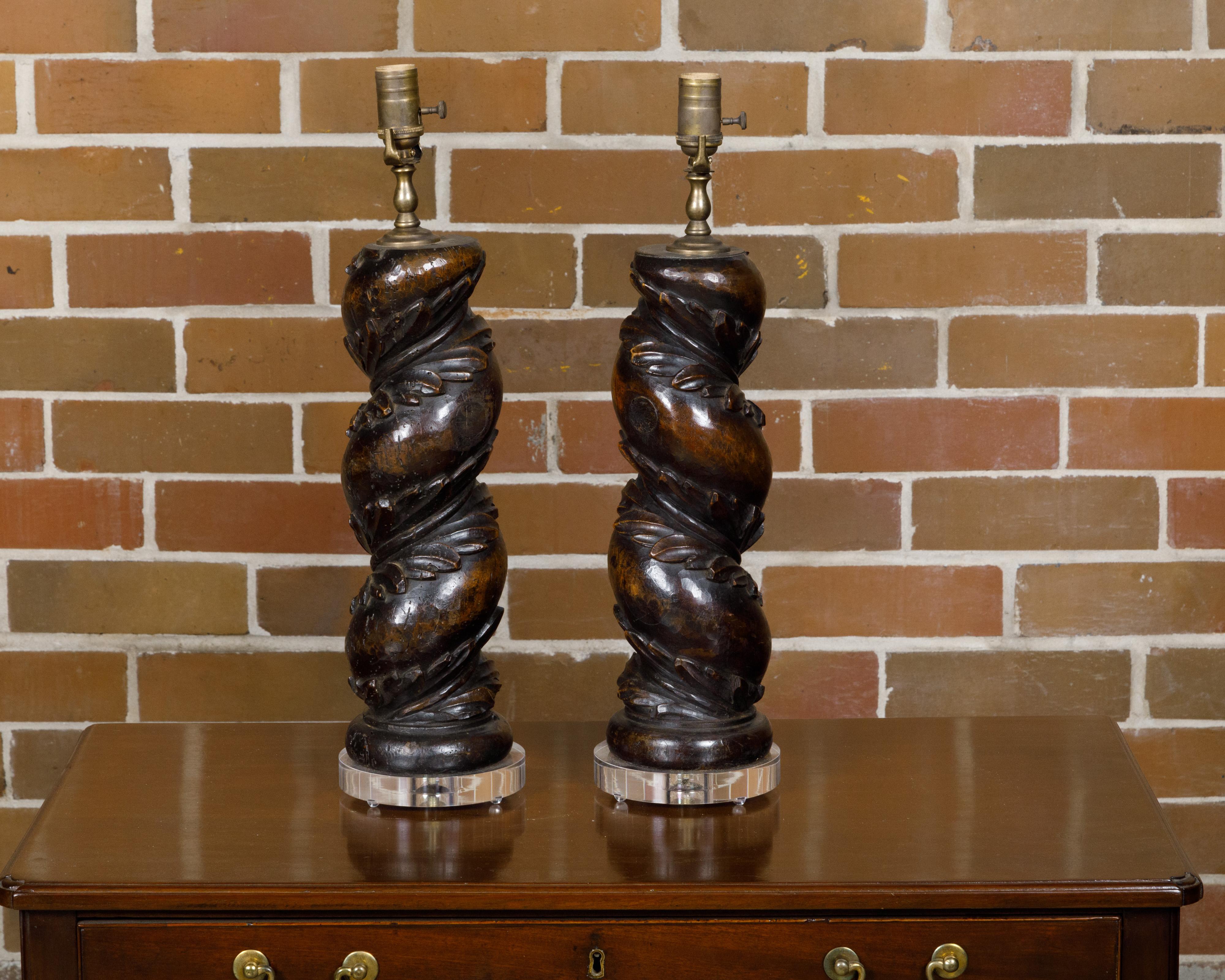 A pair of Italian walnut solomonic columns fragments from the 18th century made into US wired table lamps, raised on custom lucite bases. Charming us with their historical allure, this pair of Italian 18th-century walnut Solomonic column fragments