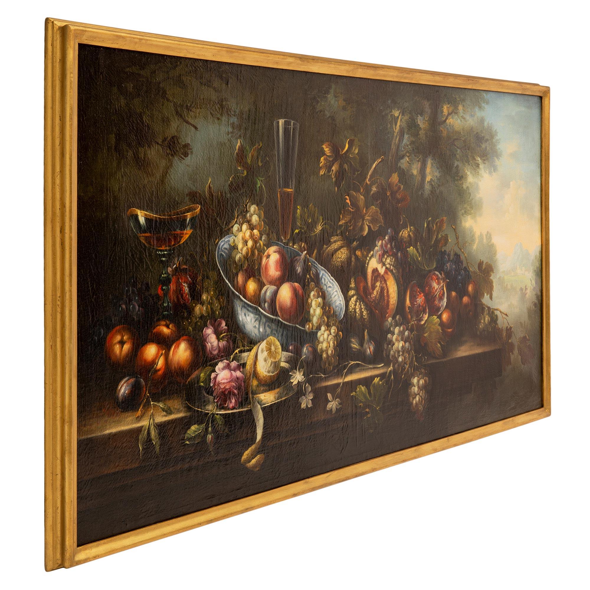 An exquisite Italian early 18th century still life oil on canvas Roman painting in its original giltwood frame. The striking painting depicts an opulent array of beautiful fruit on a banquet table in the Italian countryside. The fruits display