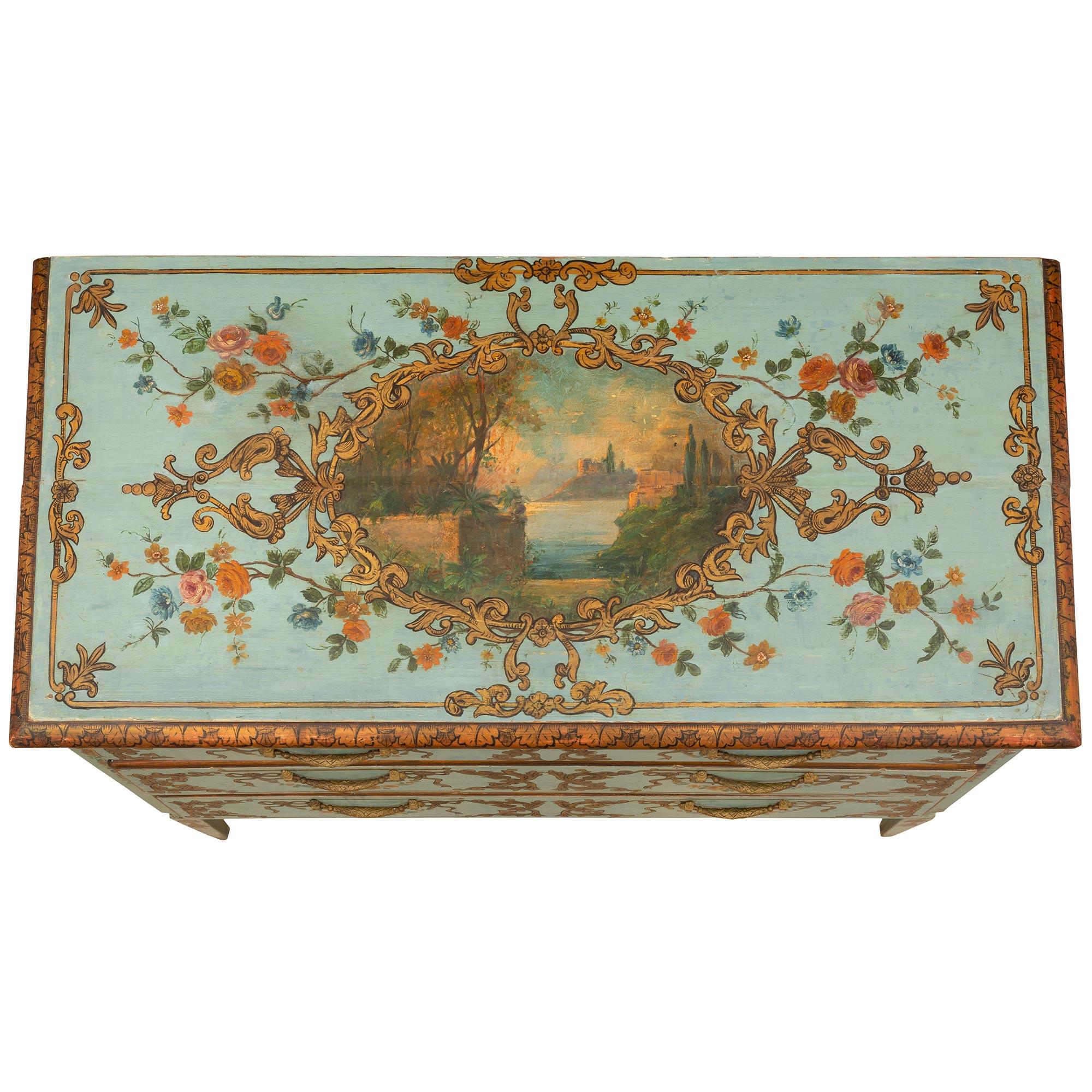 A very elaborately hand-painted mid 18th century circa. 1750 three drawers Italian chest. The chest has wonderfully painted landscape scenes on both sides and top bordered by gilt scrolled Acanthus leaves amidst finely detailed flowers. The drawers