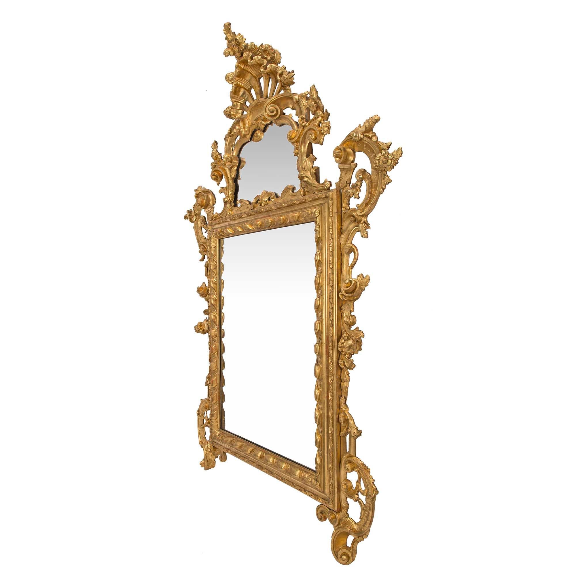 Superbe miroir italien en bois doré vénitien du XVIIIe siècle. Le miroir est décoré d'opulentes volutes feuillues de chaque côté du cadre central rectangulaire en bois de gitane. Une plaque de miroir supplémentaire est présentée sur la couronne
