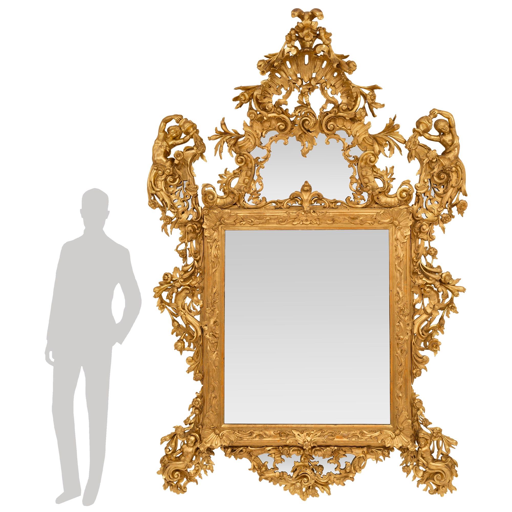 A breathtaking and monumentally scaled Italian 18th century Venetian st. giltwood mirror. The most impressive mirror retains all of its original mirror plates throughout which are set within a dramatic and extremely finely detailed carved giltwood