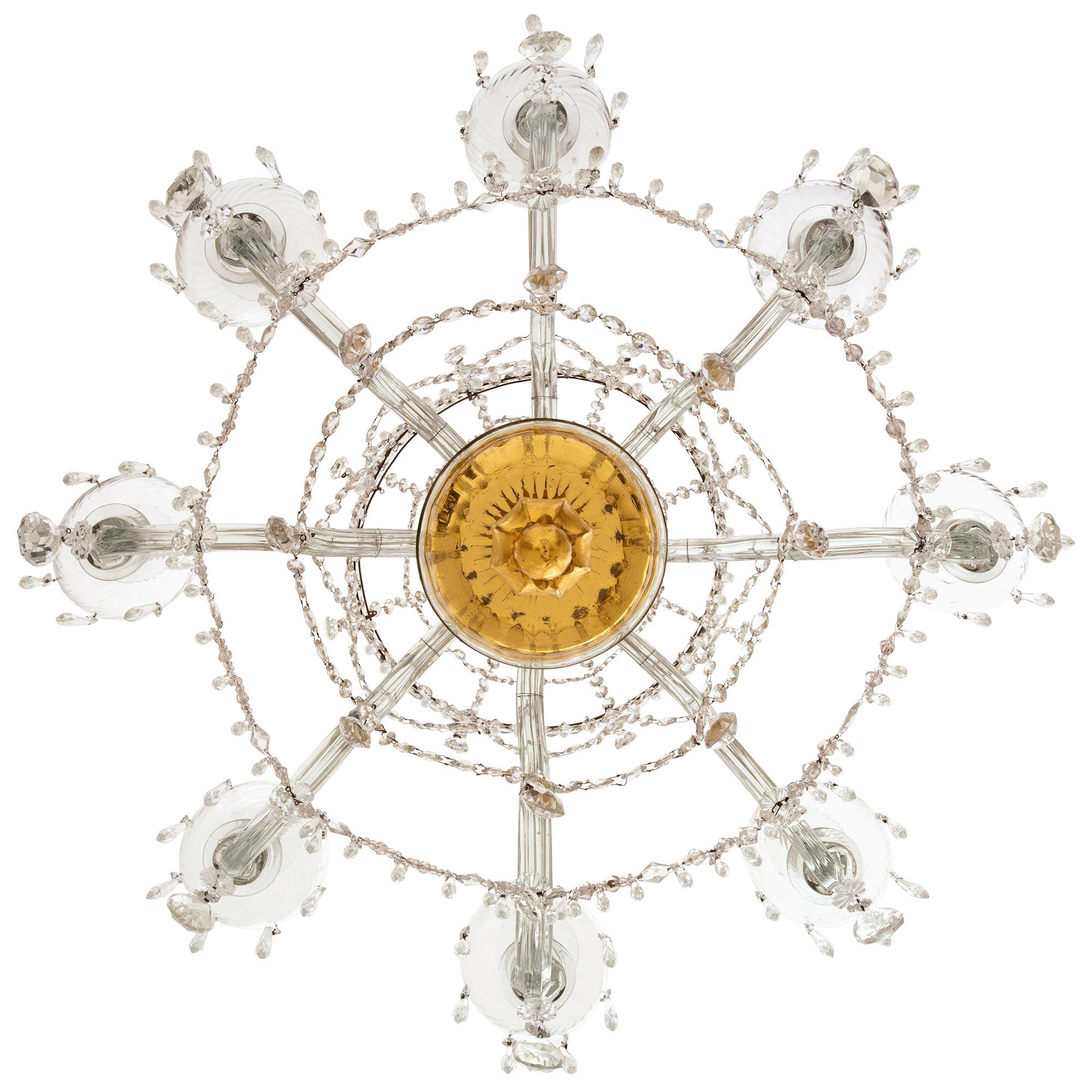 A stunning and extremely decorative Italian 18th century Venetian St. Murano glass and giltwood chandelier. The eight arm chandelier is centered by a beautiful richly carved foliate giltwood finial below the elegant curved Murano glass support and