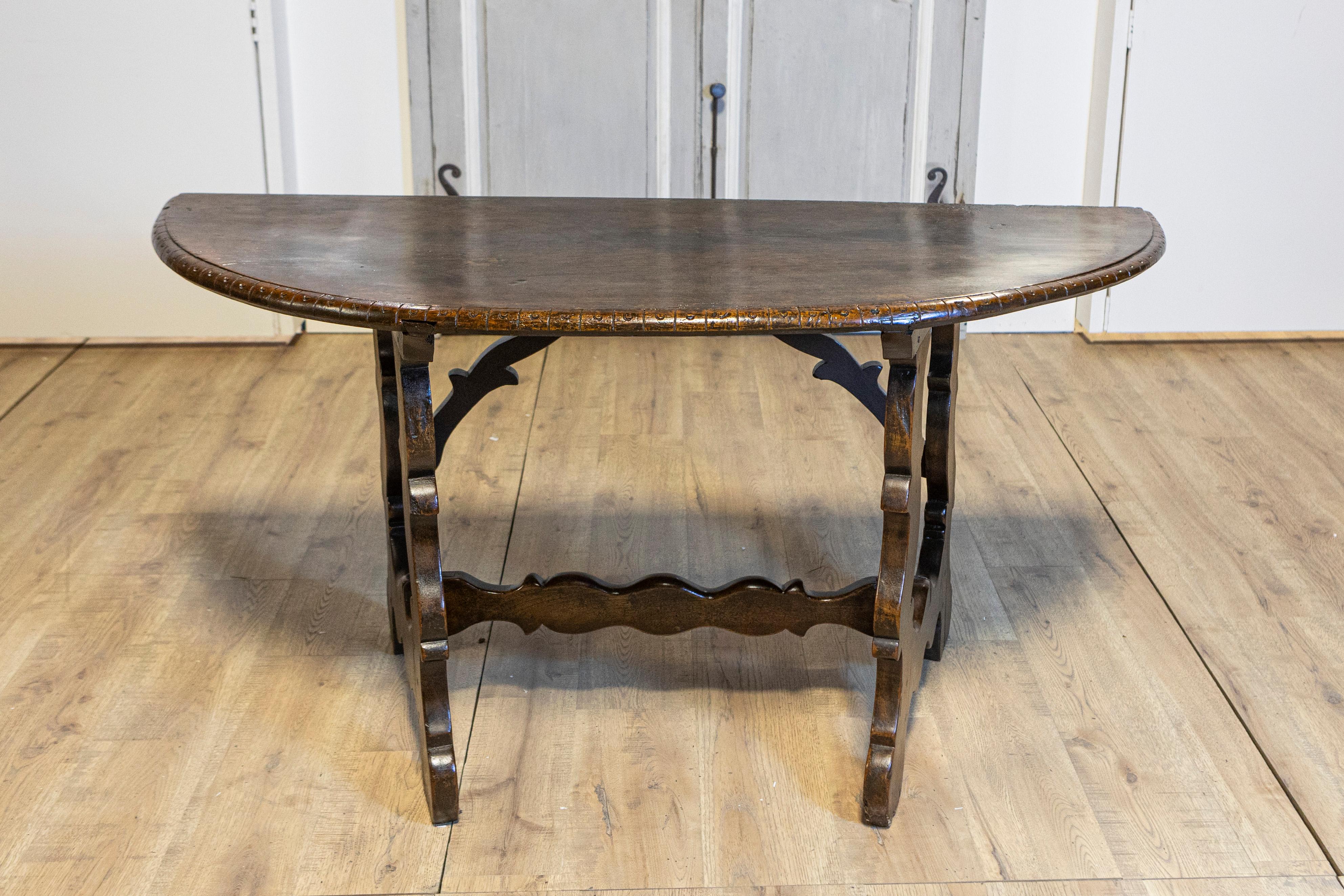 An Italian Baroque walnut Fratino console table from the 18th century with carved lyre shaped base. This exquisite Italian Baroque walnut Fratino console table from the 18th century immediately captures attention with its rich dark brown patina and