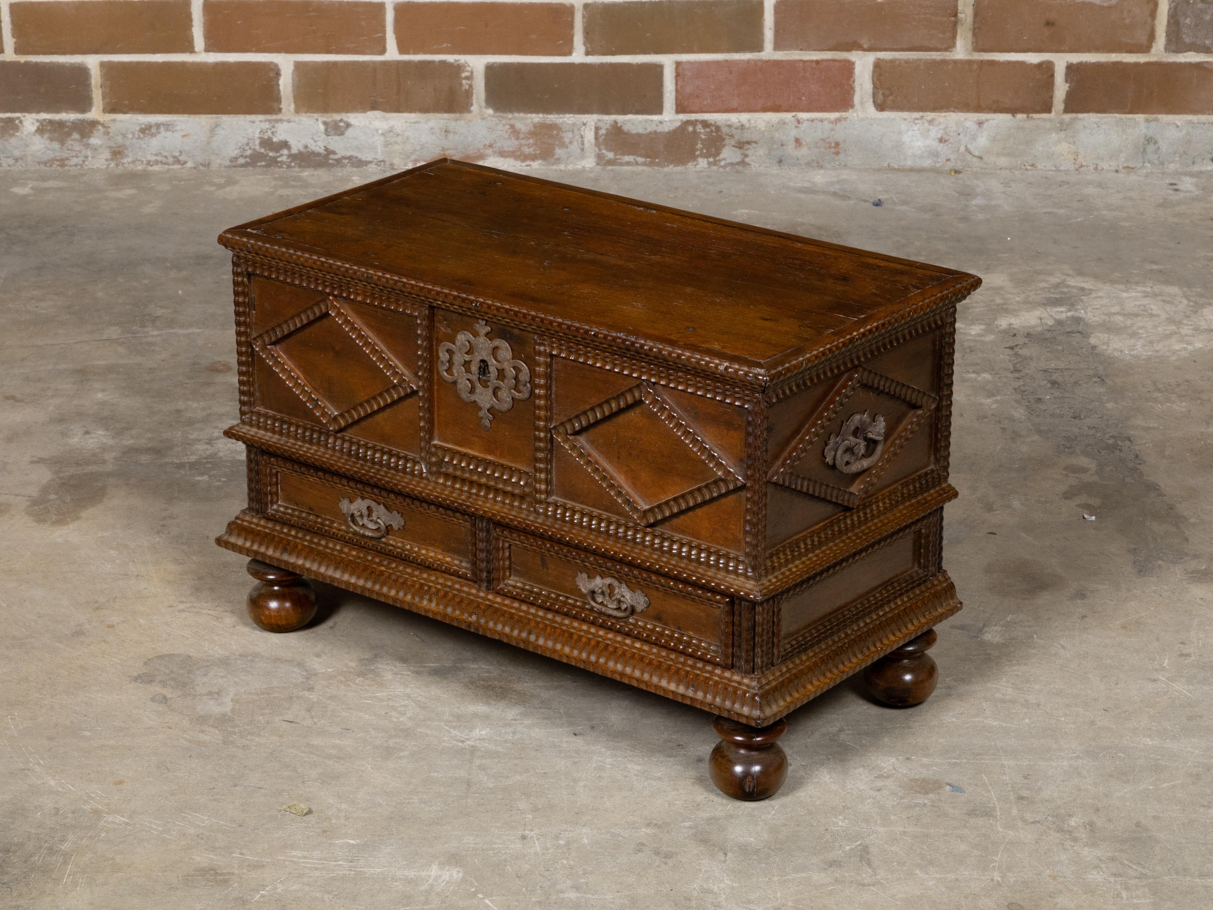 An Italian walnut coffer from the 18th century with carved diamond motifs, low drawers and ball feet. This exquisite Italian walnut coffer from the 18th century exudes timeless elegance and masterful craftsmanship. The coffer's lid opens to reveal a