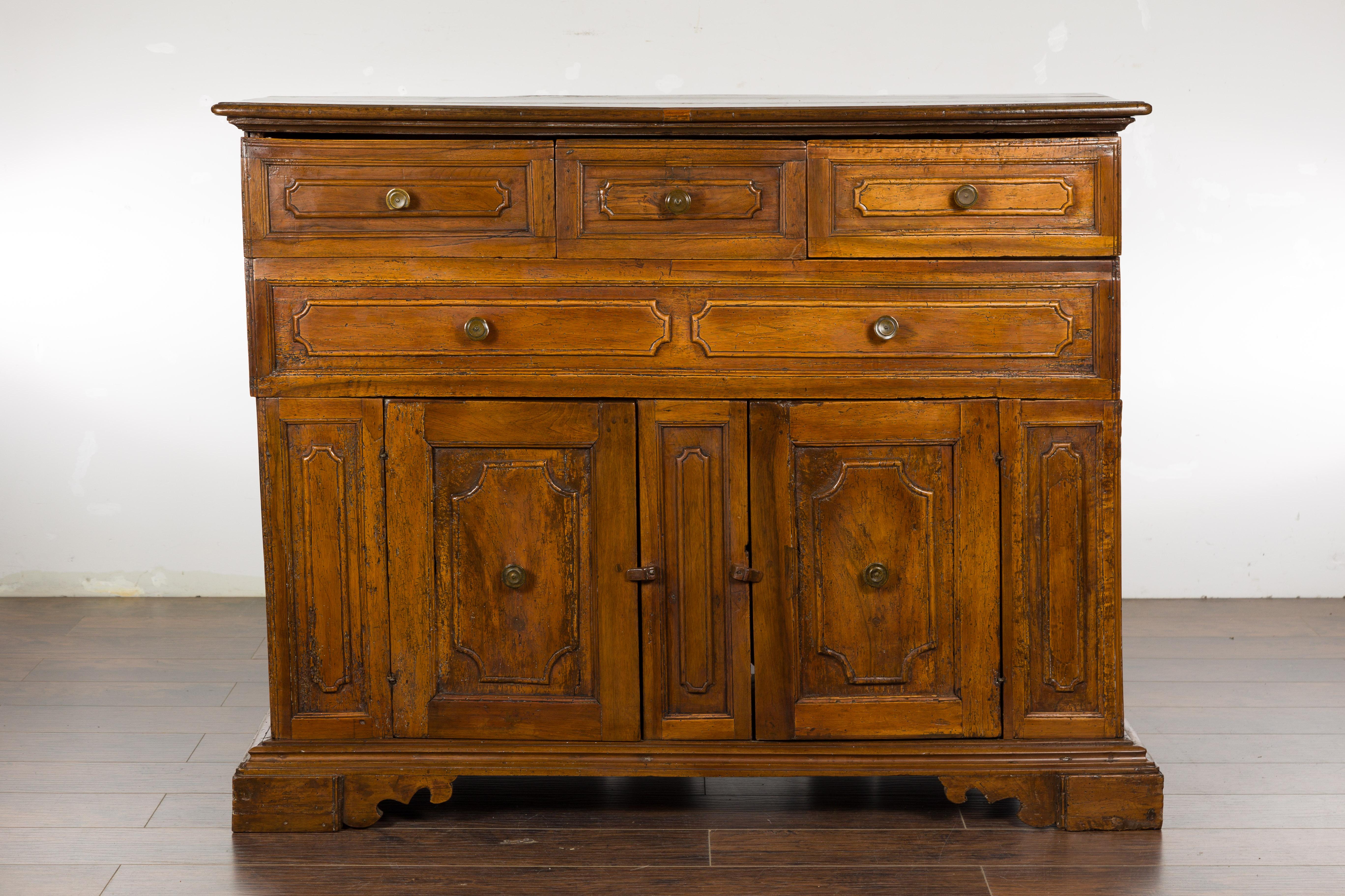 An Italian walnut credenza from the 18th century, with four drawers and two petite doors. Introducing an exquisite piece of history and Italian craftsmanship, this 18th-century Italian walnut credenza is a symphony of design that speaks volumes of