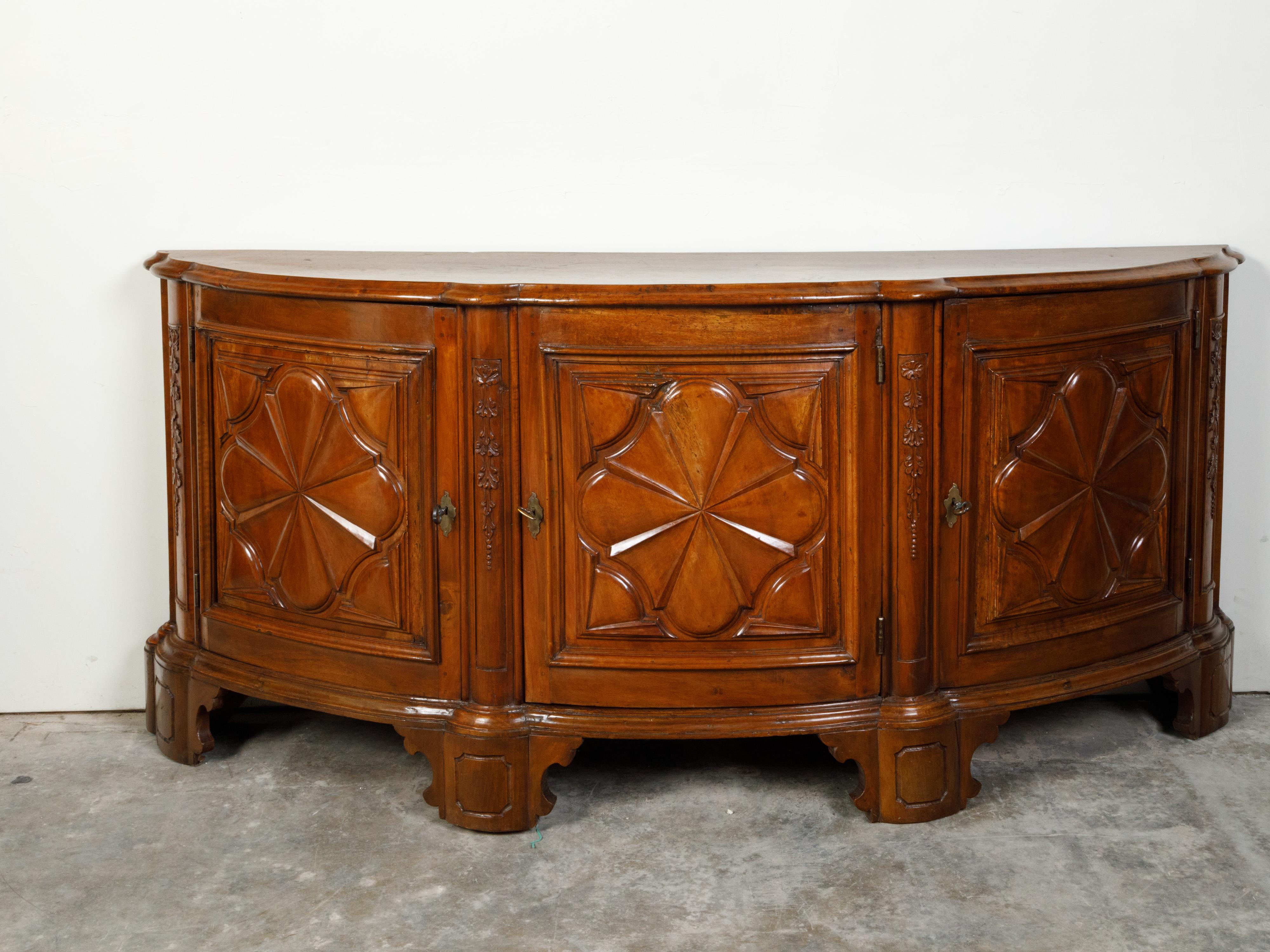 An Italian walnut demilune credenza from the 18th century, with carved panels and three doors. Created in Italy during the 18th century, this walnut credenza features a semi-circular top sitting above three doors, beautifully adorned with carved
