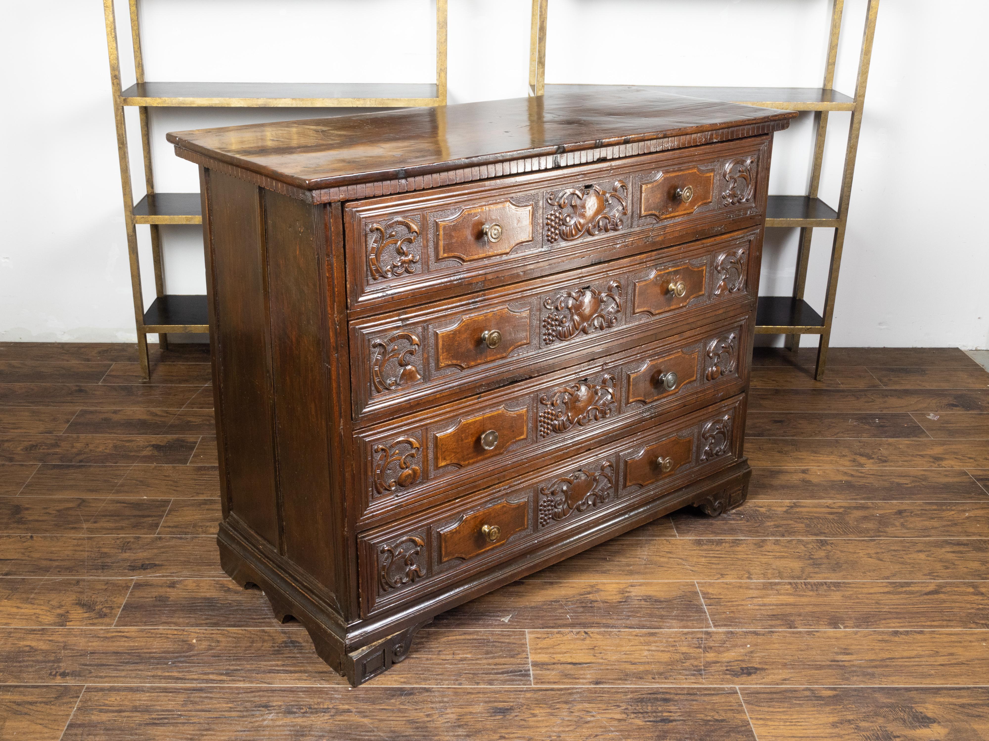 An Italian walnut commode from the late 18th century, with carved scrolls and grape motifs. Created in Italy during the later years of the 18th century, this walnut commode features a rectangular top sitting above a dentil style molding. The façade