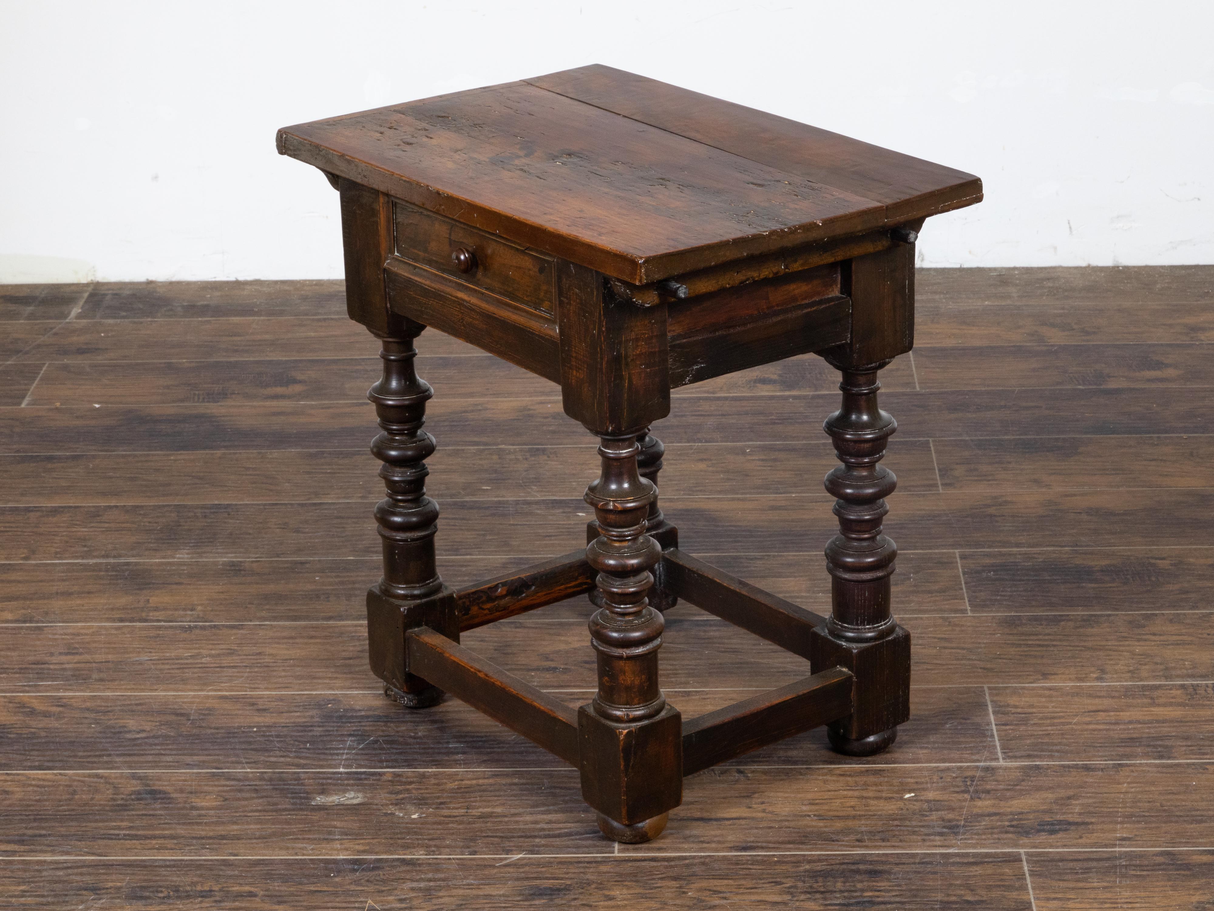 An Italian walnut side table from the 18th century with single drawer and recessed panel, four turned legs, rectangular block joints, plain side stretchers and weathered patina. This Italian walnut side table hailing from the 18th century, instantly