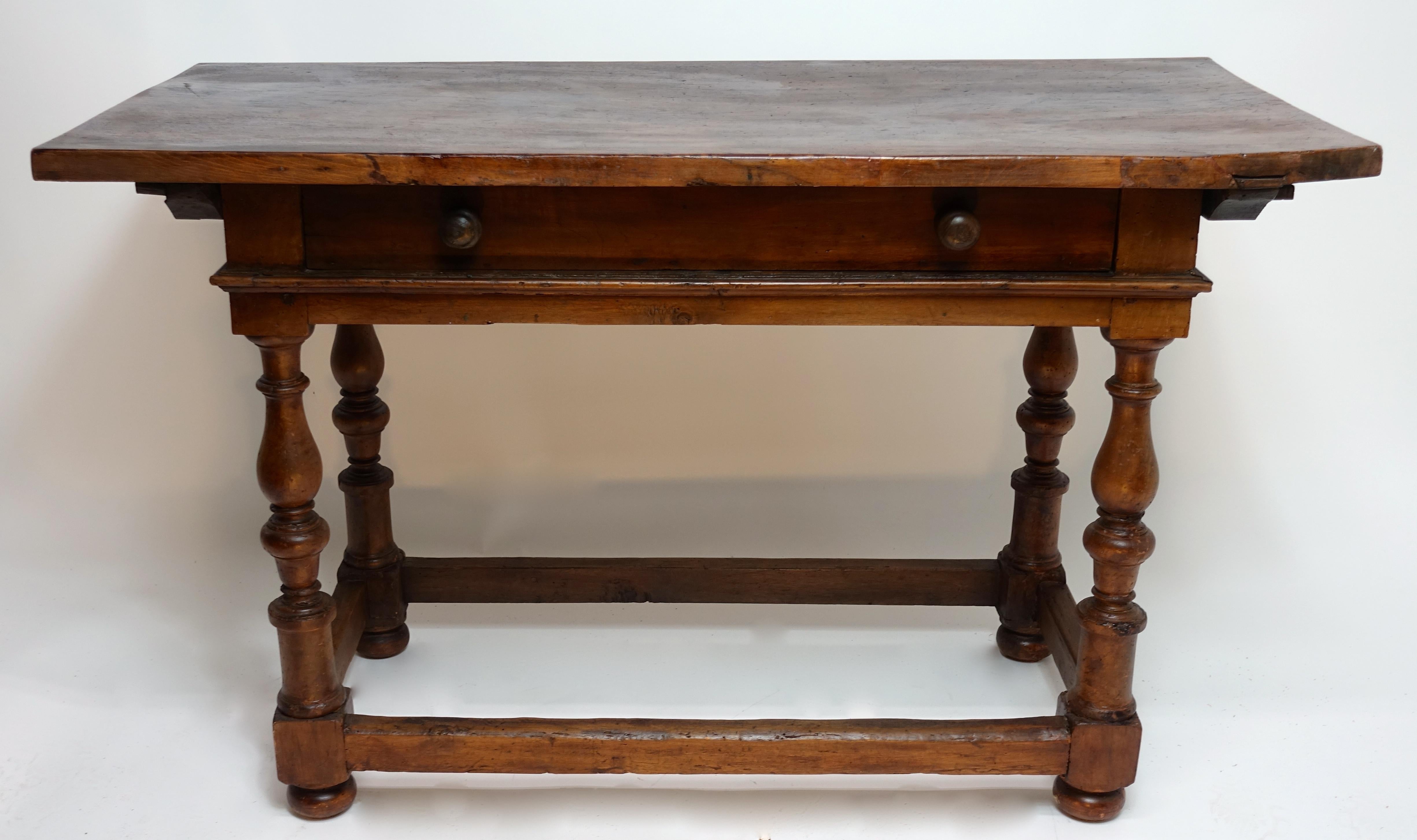 Wonderful 18th Century Italian Walnut table with a large single drawer, the top removable and fastened with wood pegs, hand carved turned legs with low stretchers sitting on bun feet. 


