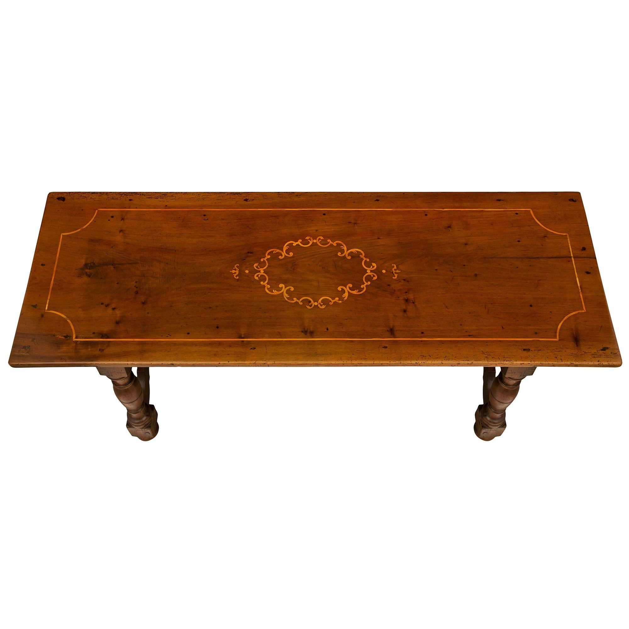 An extremely handsome Italian 18th-century walnut trestle table. The table is raised on four bun feet below turned legs connected by scalloped shaped slanted supports. Above the arbalette shaped frieze is the rectangular solid top decorated with