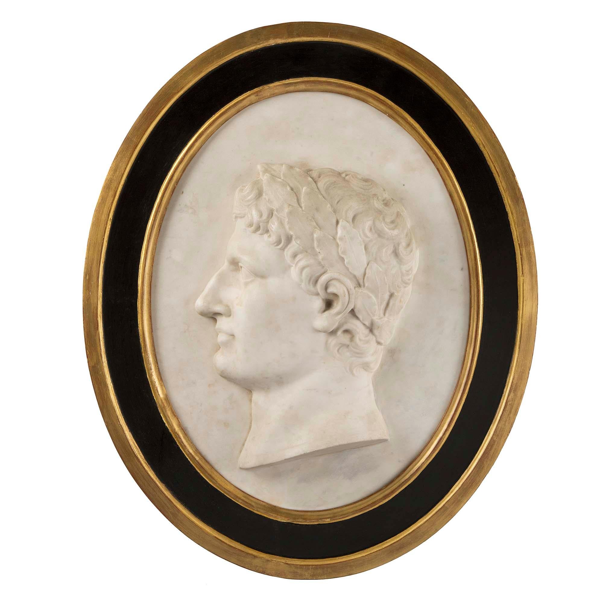 A very handsome Italian 18th century white Carrara marble and giltwood plaque. This finely carved white Carrara marble plaque depicts a young Caesar. All within a black patinated oval frame with moulded giltwood borders. All original patina and gilt