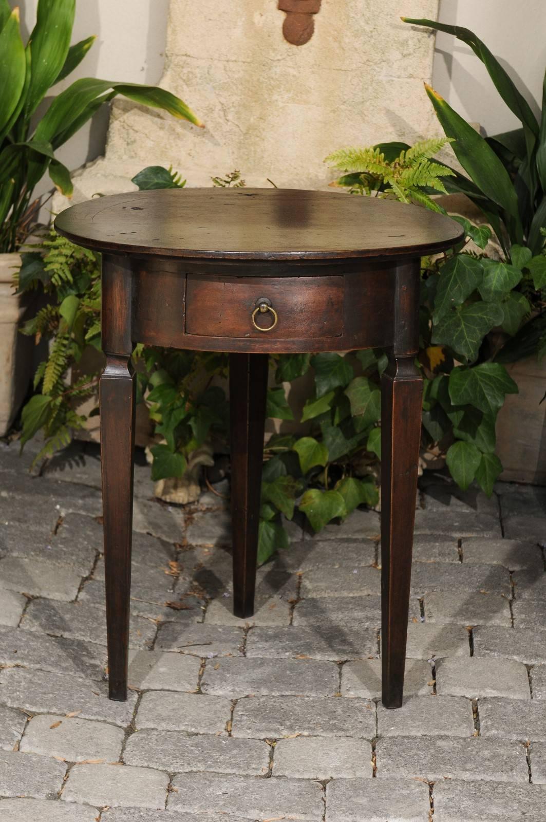 An Italian oak and walnut guéridon side table with circular top, single drawer and tapered legs from the early 19th century. Born in the early years of the 19th century, this Italian guéridon table features a round top showing good aging, sitting