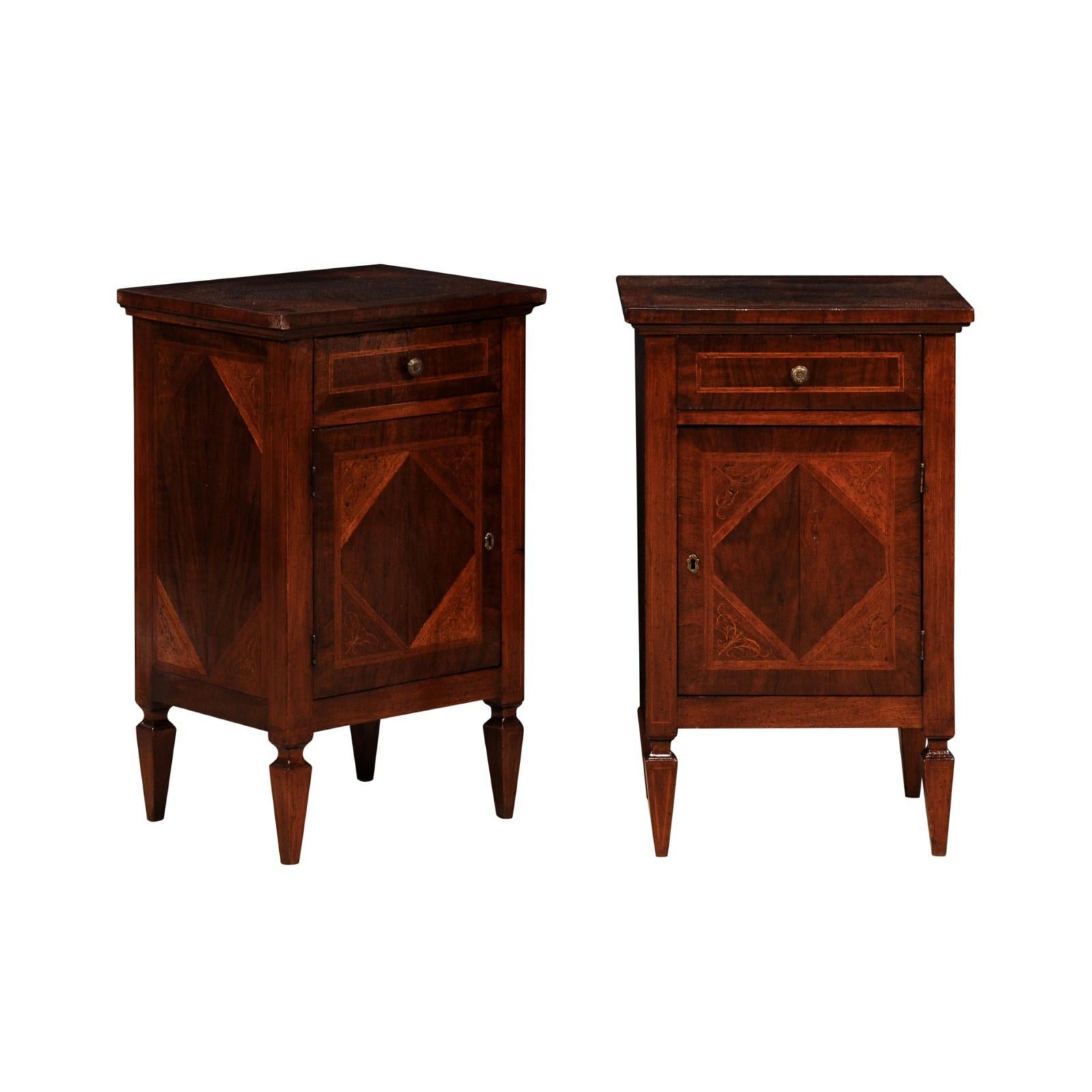 A pair of Italian walnut nightstand tables from circa 1900 with mahogany inlay, scrolling foliage marquetry, single drawers and single doors. Step back in time with this exquisite pair of Italian walnut nightstand tables from circa 1900, a testament