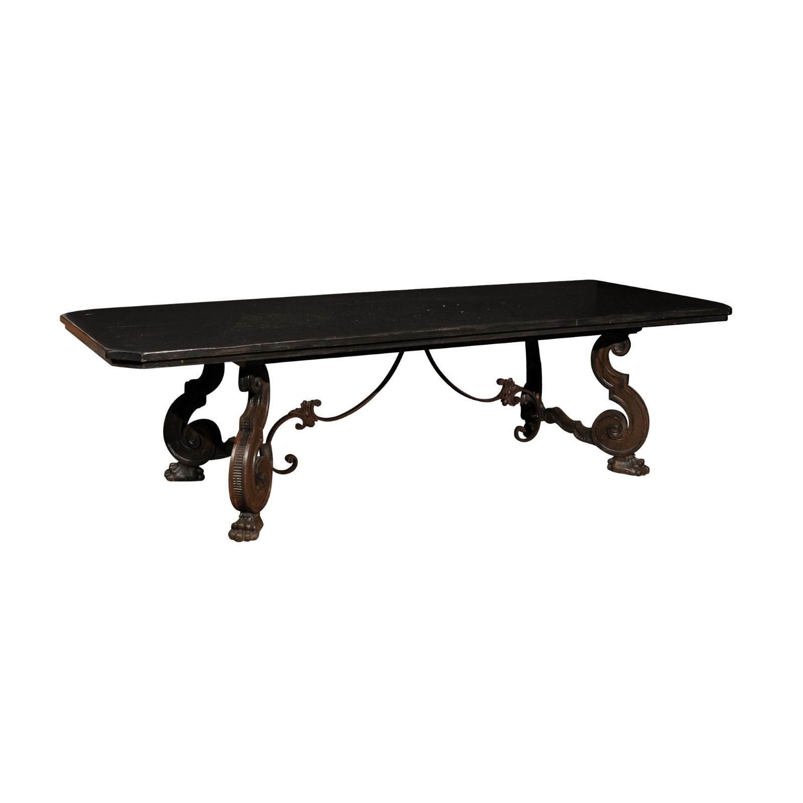 Italian 1920s walnut dining room table with bold ebonized finish, carved S-Scroll legs on paw feet. Immerse yourself in the grandeur of the 1920s with this Italian dining table, a statement piece that marries bold aesthetics with traditional