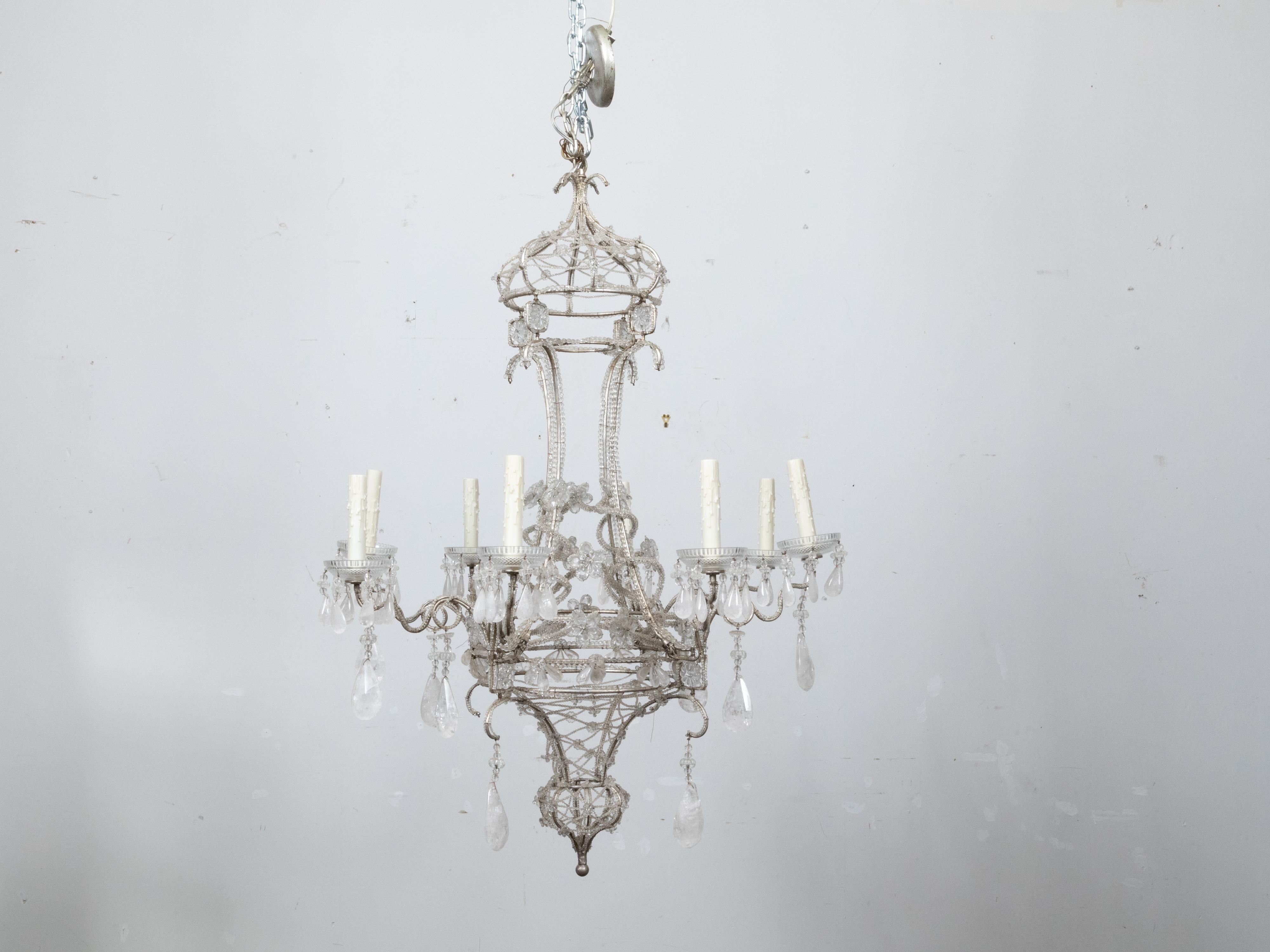 An Italian 1920s rock crystal eight-light chandelier with petite beads draping the silvered metal frame. Elevate your interior decor with this exquisite Italian 1920s rock crystal eight-light chandelier, an illustrious embodiment of elegant design