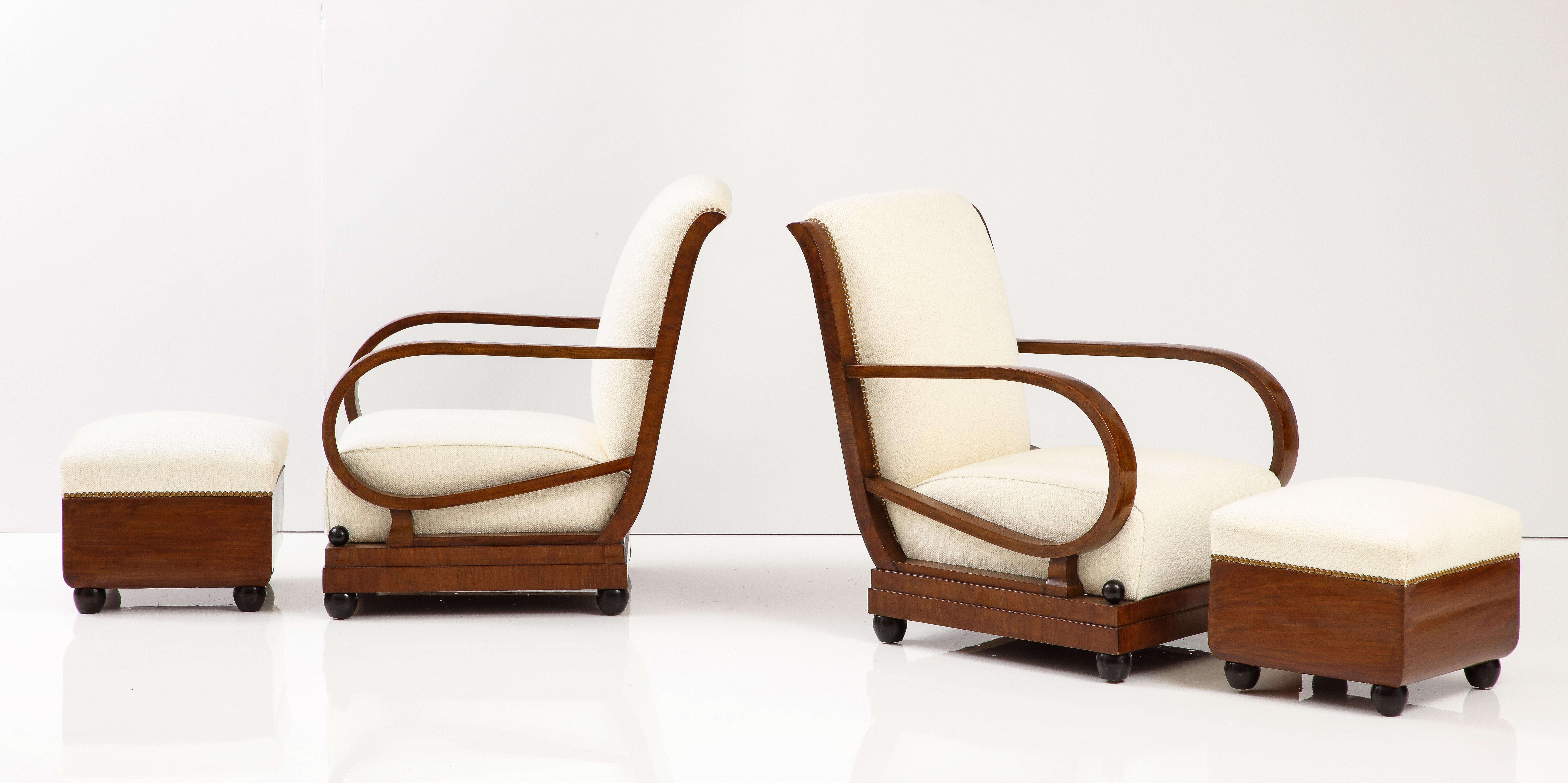 Italian 1920's pair of armchairs / lounge chairs and matching pair of foot stools / ottomans. From the early Art Deco period of Northern Italy, the rich walnut is finely carved and highlights the woods natural beauty, the armchairs backs are