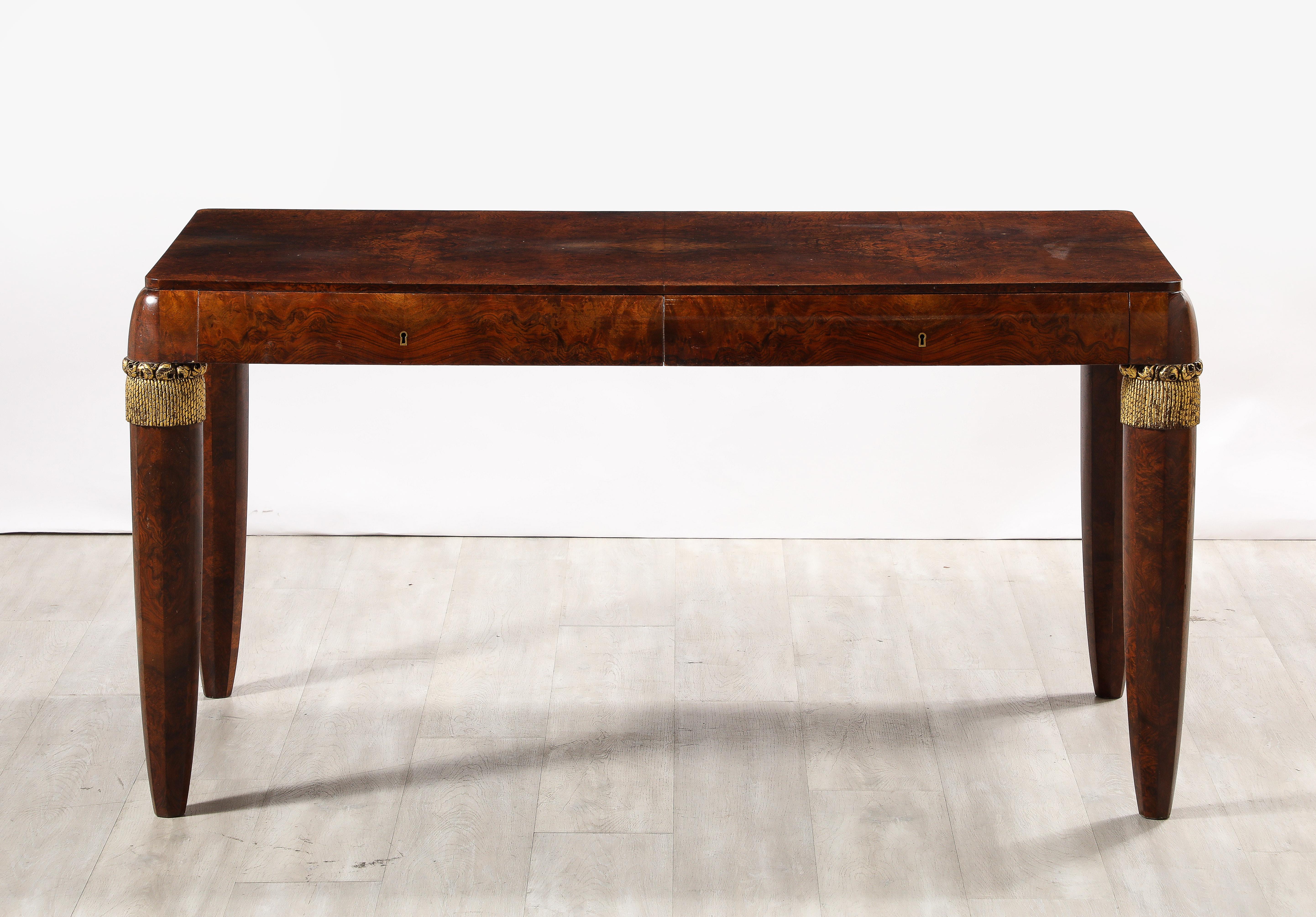 A very fine Italian 1930's burl walnut writing table or desk, the large rectangular surface is supported by an elegantly curved apron consisting of two large drawers atop robust angled legs with brass banding decoration at the top of chic tassel
