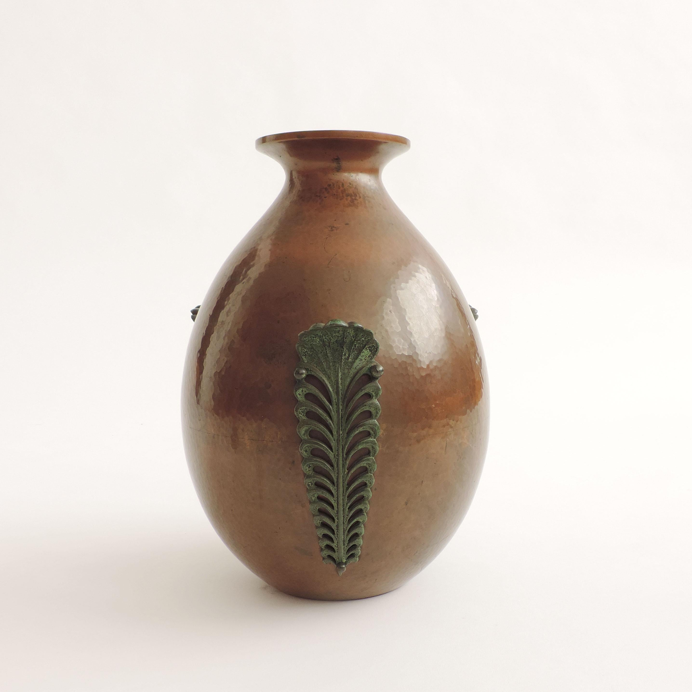 Vase en cuivre martelé italien des années 1930.
Trois feuilles décoratives en métal sont appliquées avec trois boutons ronds en métal.
Pièce non signée.
 