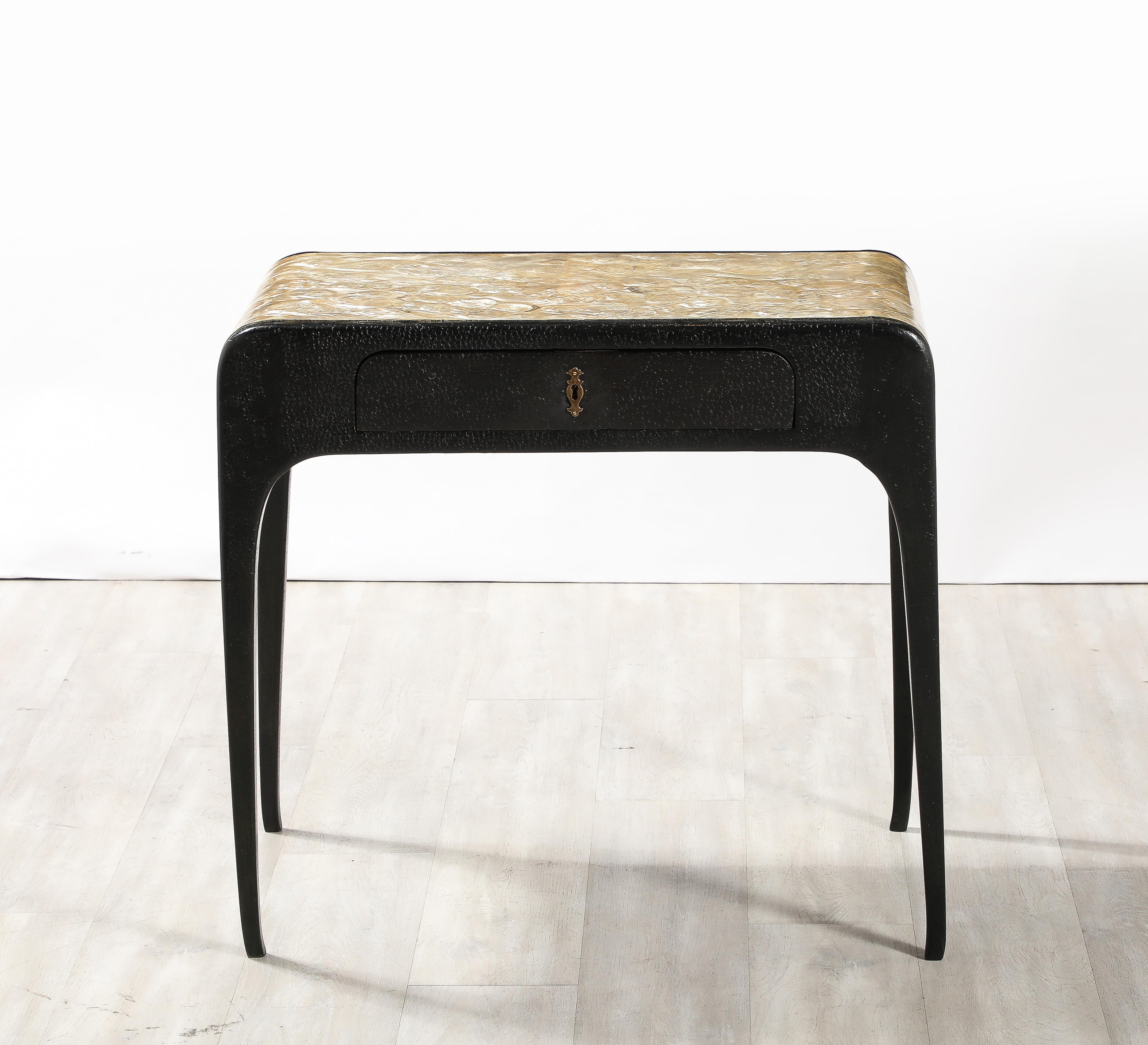 A highly unique and rare Italian 1930's console or vanity table; the exquisite mother of pearl surface cascades down the sides creating a waterfall effect; the apron and legs of hand-carved, lacquered wood resembling a snakeskin or fish scale