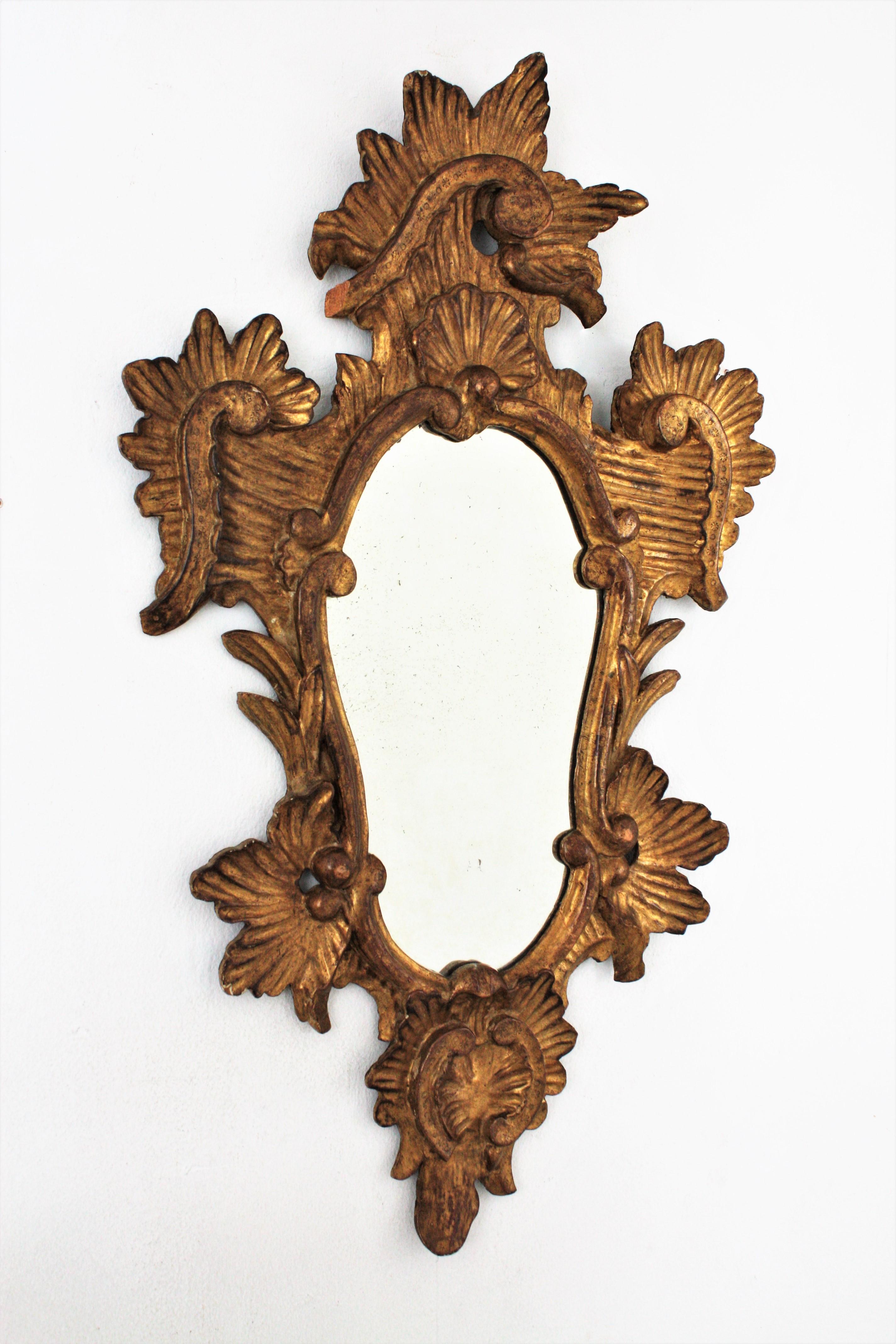 Impressionnant miroir mural ou miroir console en bois finement sculpté et doré de style Rococo. Italie, années 1930-1940.
Ce cadre très décoratif en bois sculpté de rinceaux et de feuilles est recouvert de gesso et présente une belle patine antique