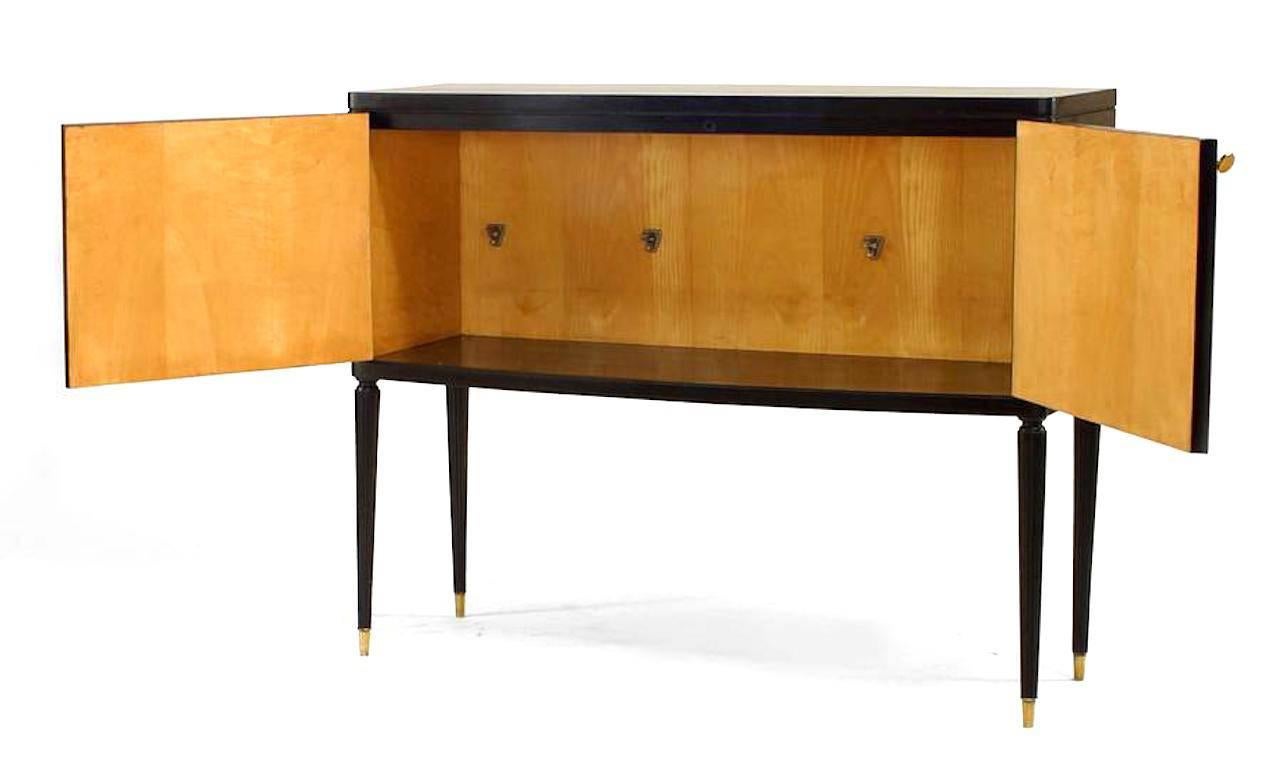 Italian 1940s ebonized commode with two fluted design doors supported on fluted legs with brass sabot feet and sycamore interior.

Labeled: Luigi Pagani/Fabbrica Mobili/Nova Milanese