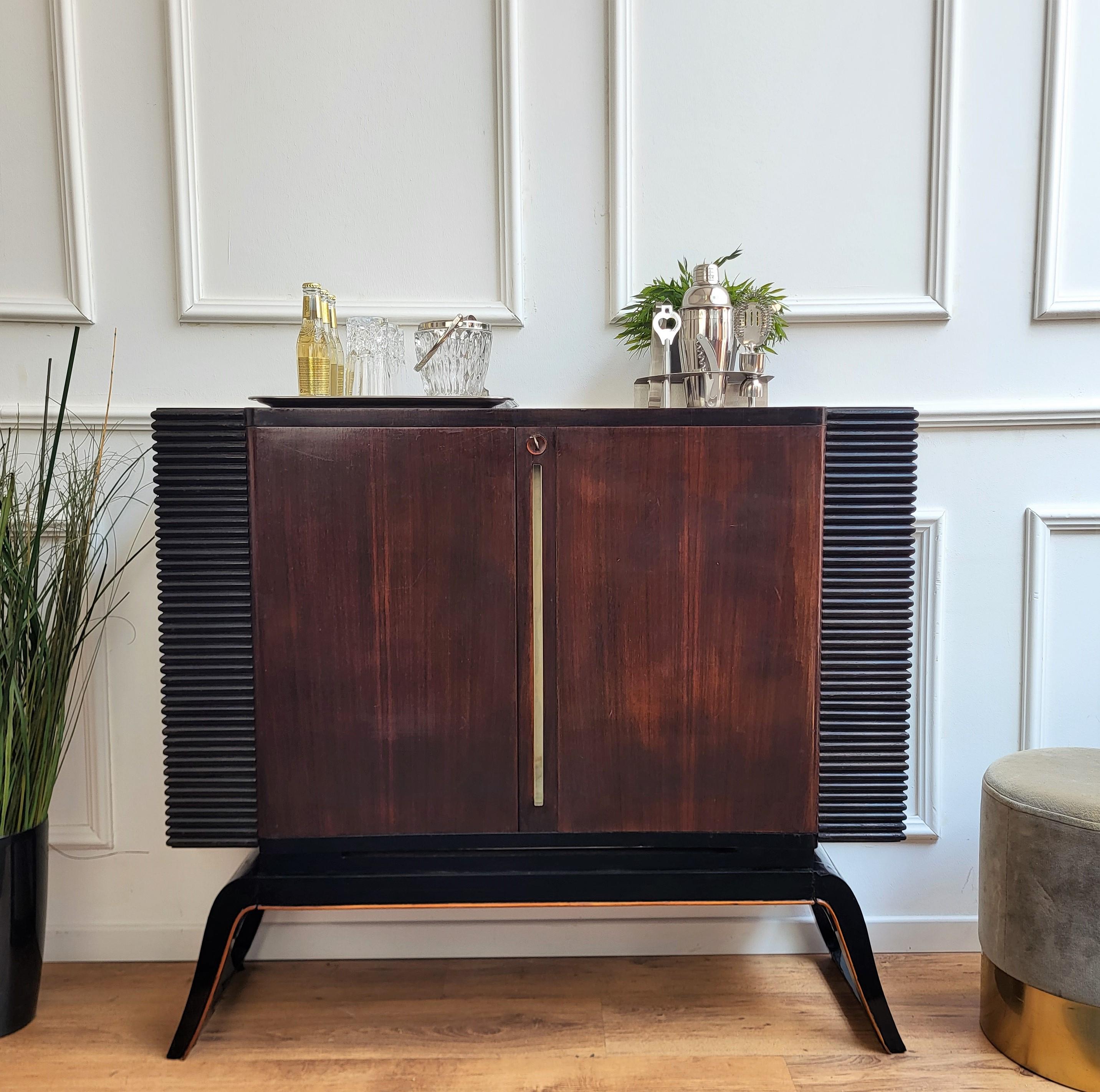 Very elegant Italian Art Deco Mid-Century Modern drinks dry bar cabinet with beautifully carved slatted walnut wood with two central doors. When opened, on the inside, as well as on the doors, we have glass and wooden shelves for bottles and