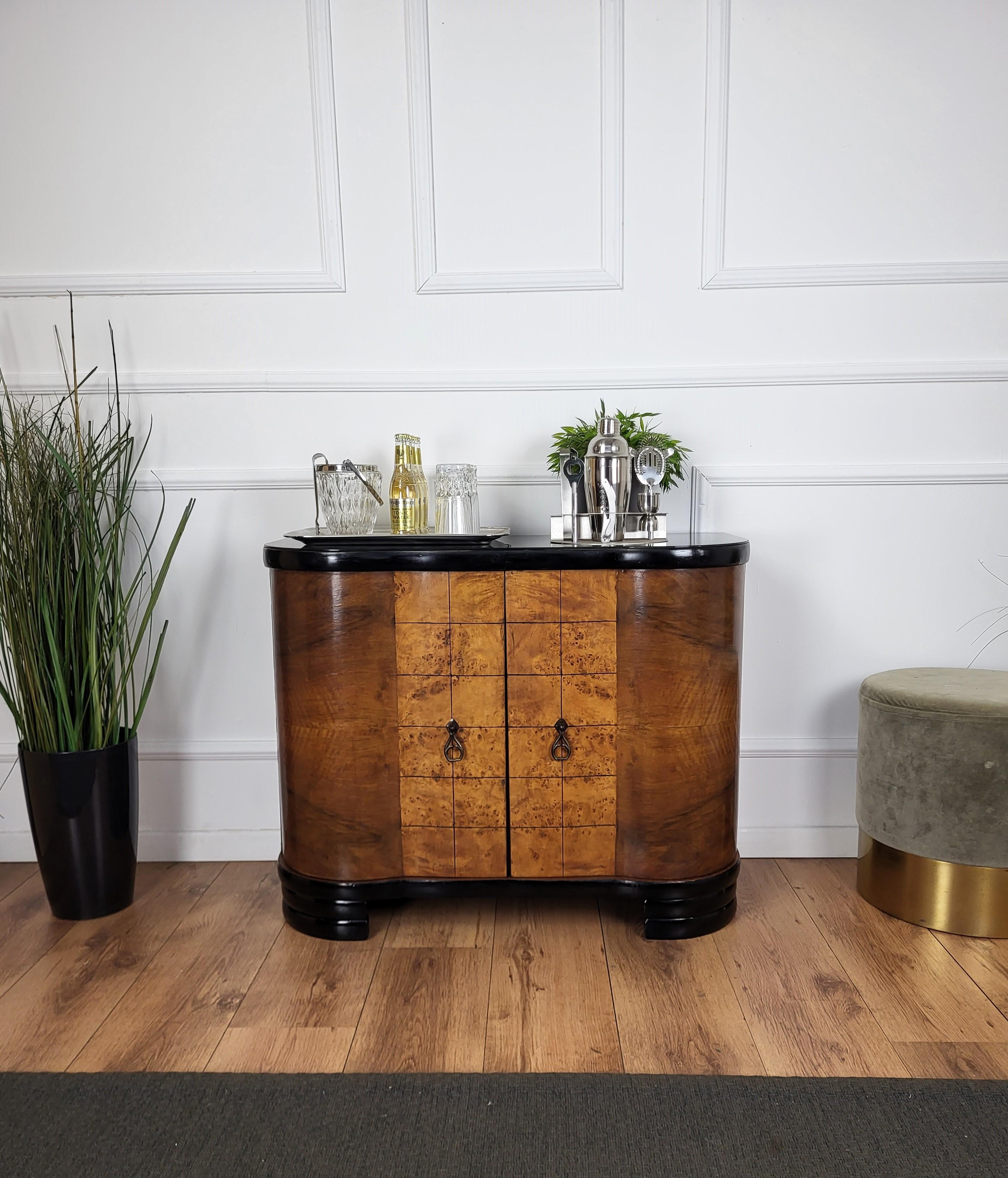 Very elegant Italian Art Deco Mid-Century Modern drinks dry bar cabinet with beautiful veneer walnut briar burl wood, black glass top, two doors and great central wooden decor craftmanship and brass handles. When opened, on the left side an amazing