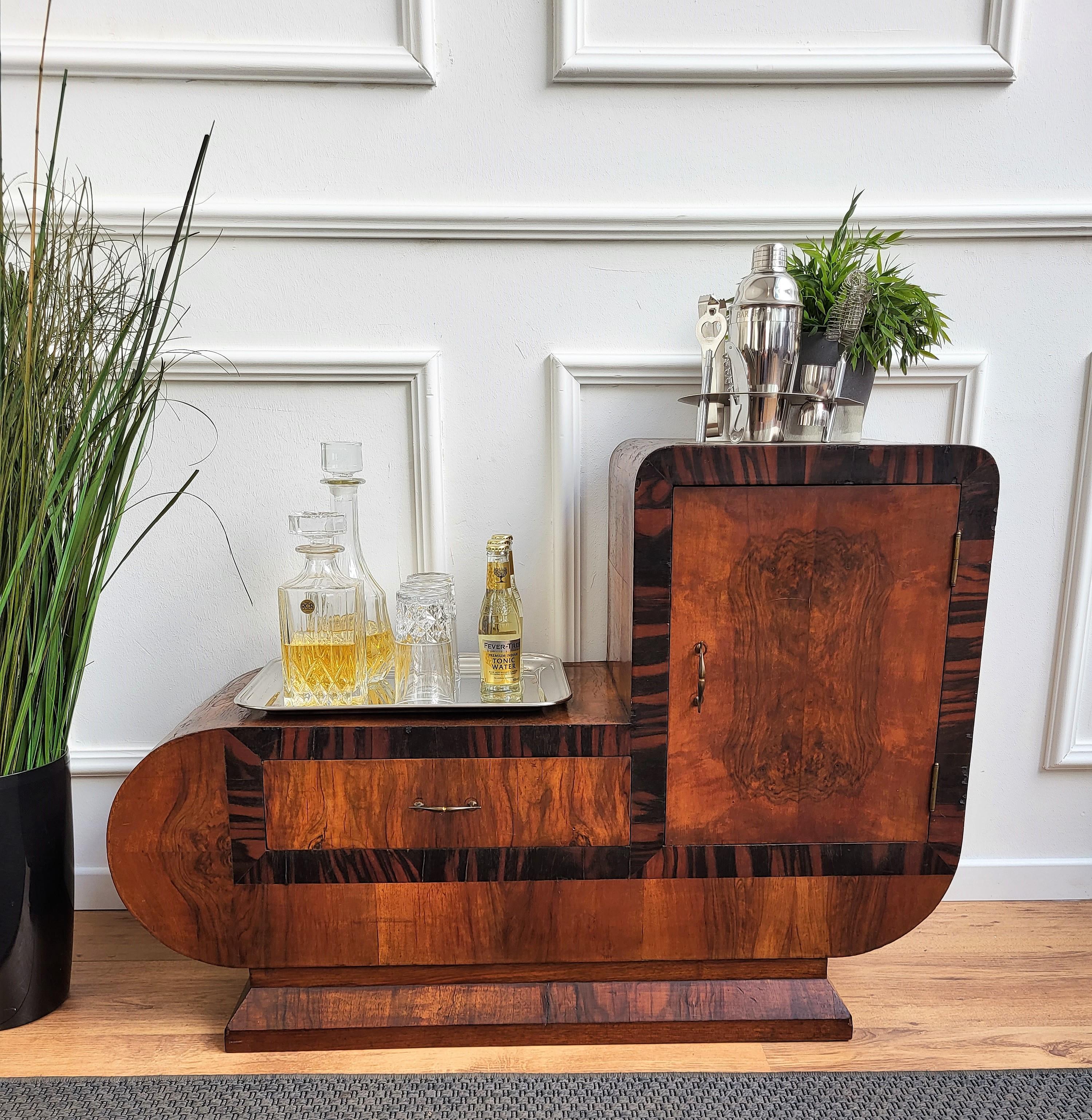 Very elegant Italian dry bar cabinet in typical Art Deco shape and materials with its beautiful veneer walnut briar burl wood, one door and a drawer both framed with wood veneer. The Art Deco style, that preceded Hollywood Regency and thereafter