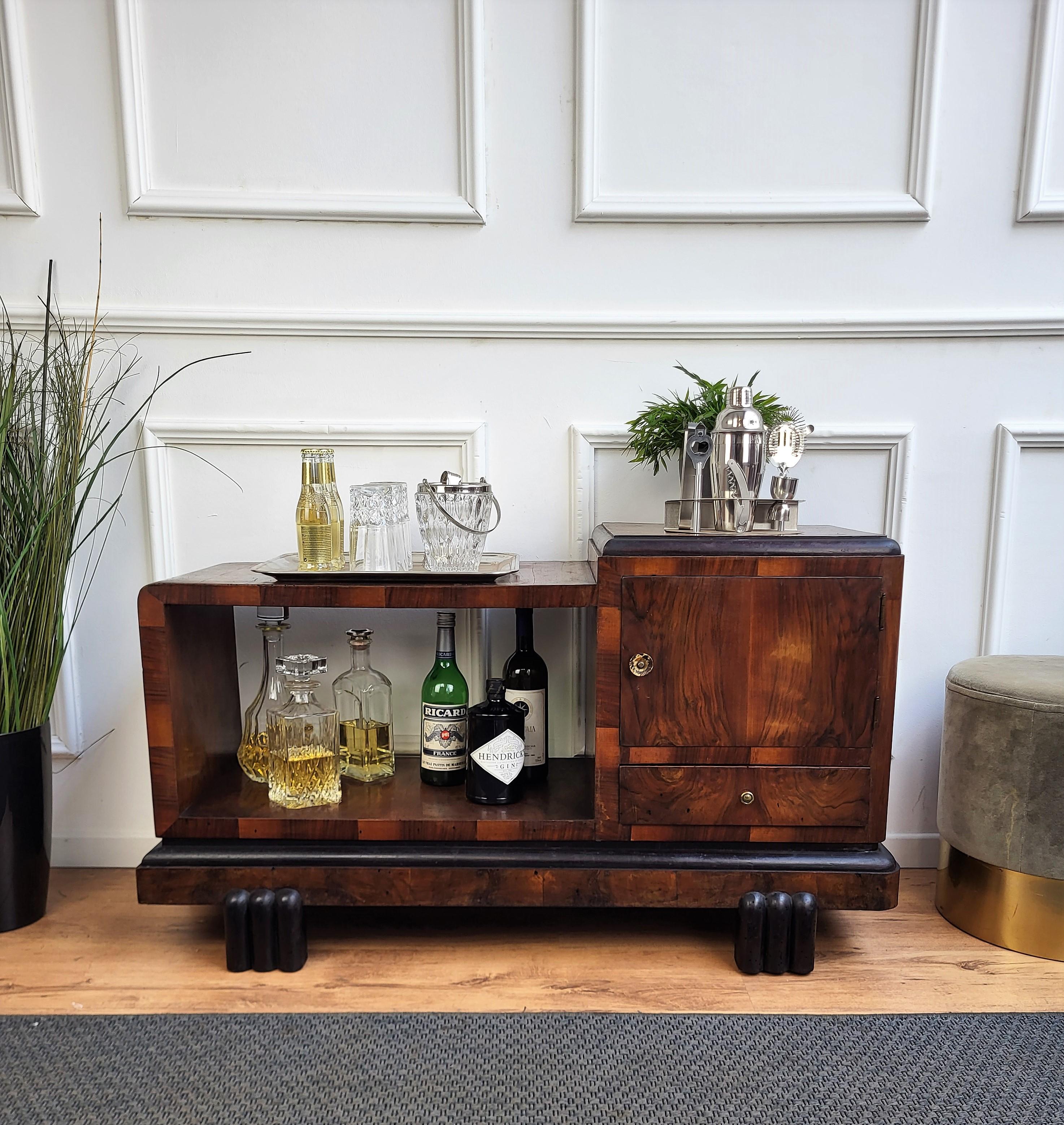 Very elegant Italian dry bar cabinet in typical Art Deco shape and materials with its beautiful veneer walnut briar burl wood, one door and a drawer both framed with wood veneer standing on 4 amazing feet. The Art Deco style, that preceded Hollywood