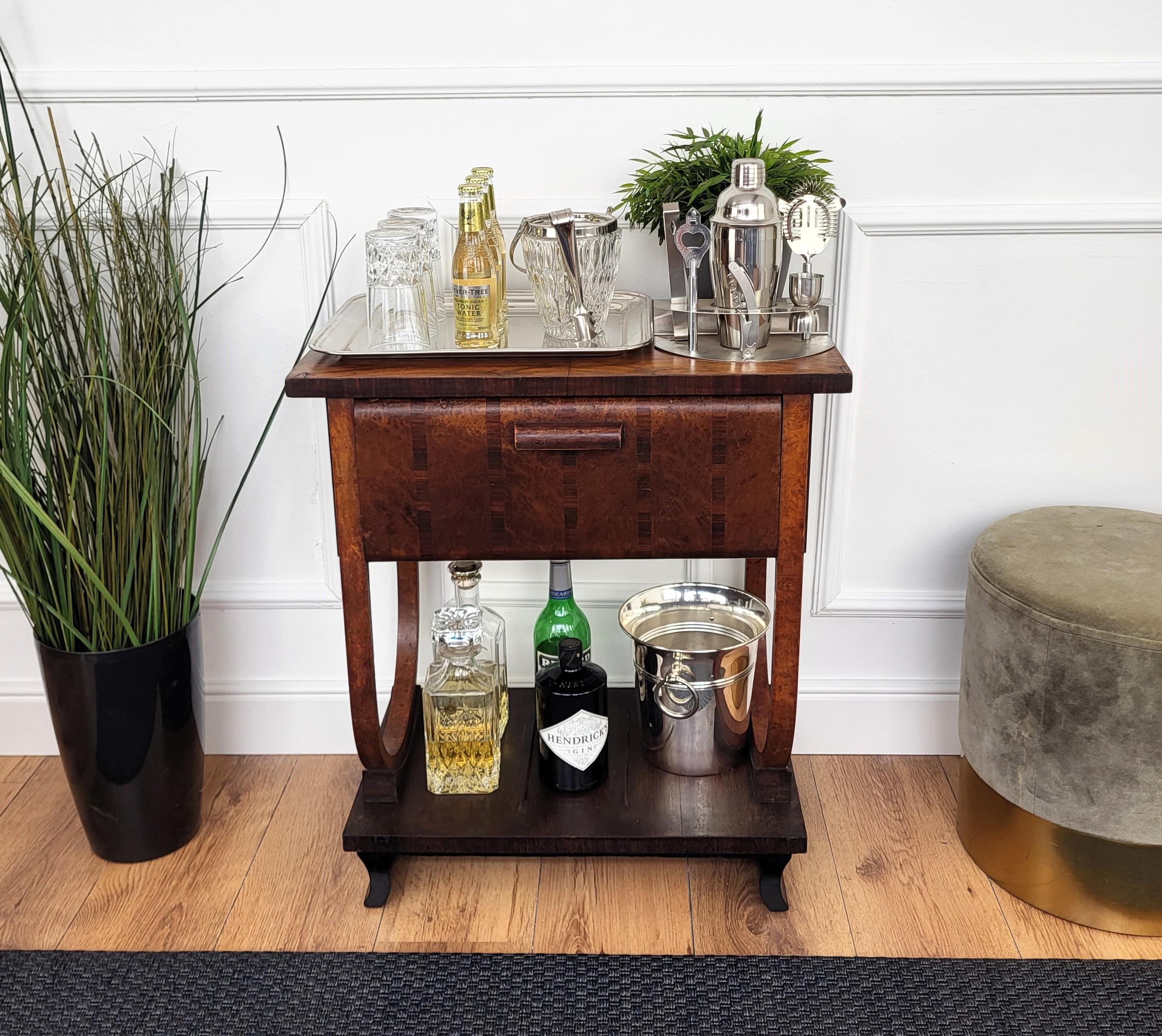 Sehr eleganter italienischer Beistelltisch in typischer Art Deco Form und MATERIAL mit seinem schönen Holz, einer Tür mit typischem Deco'-Griff und der insgesamt armonisch geschwungenen Hauptstruktur, die die Regale hält. Der Art-Déco-Stil, der dem