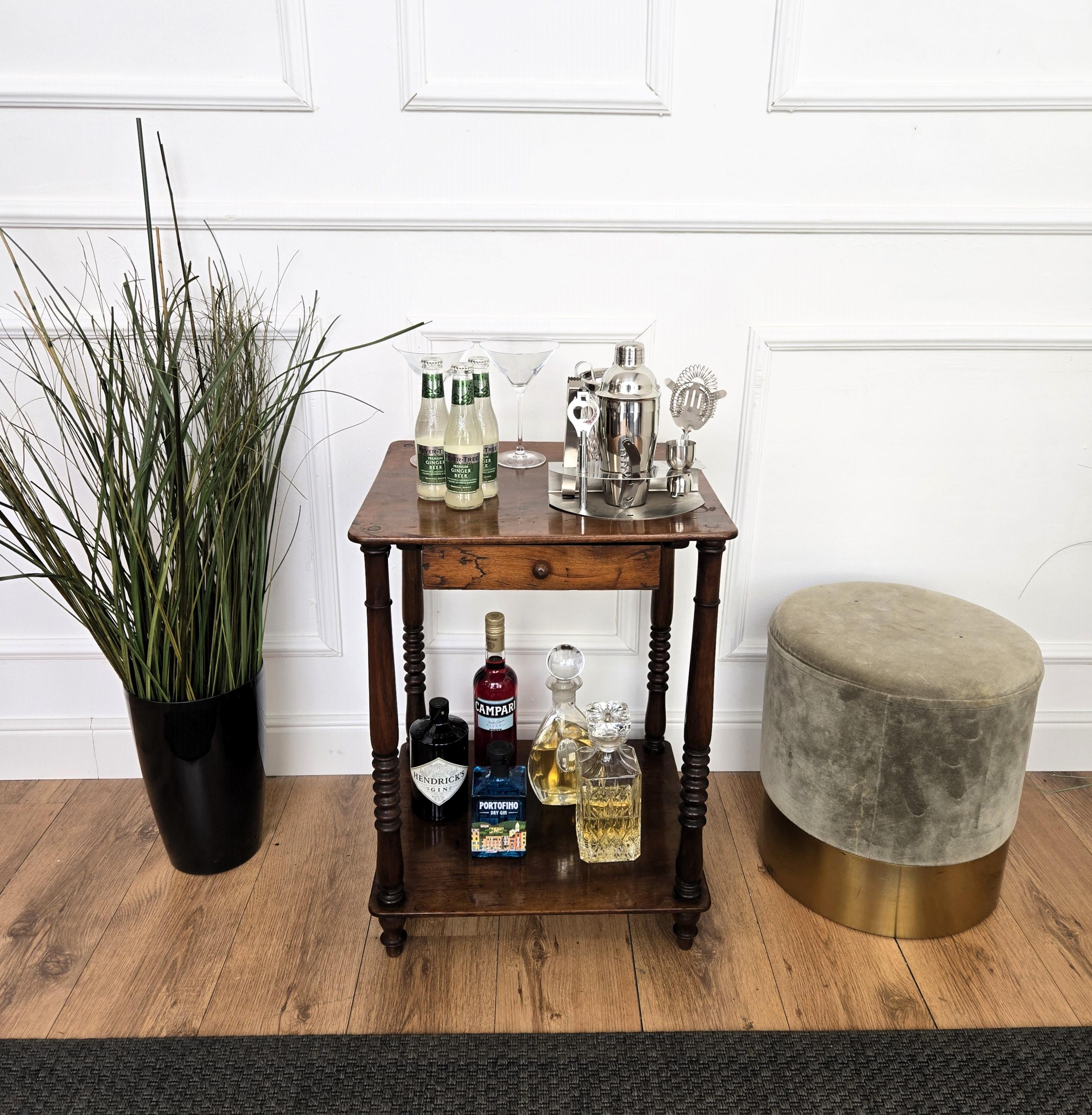 Très élégante table d'appoint italienne aux formes et matériaux typiques de l'Art Déco avec son beau bois, son tiroir central et l'harmonie de l'ensemble soulignée par les pieds sculptés supportant les étagères. Le style Art déco, qui a précédé le