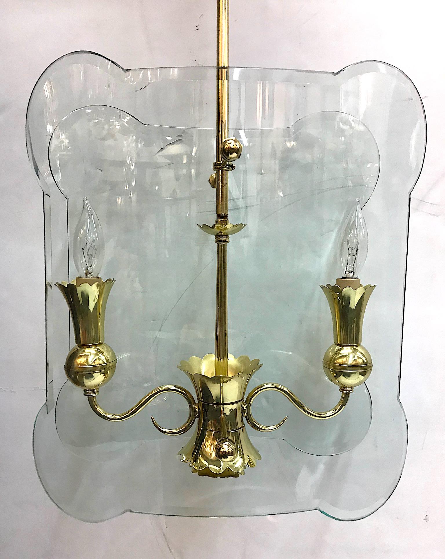 A lovely Italian 1940s brass two-light lantern / pendant light with glass panels. Each glass panel is meticulously cut with rounded corners, beveled edge and curved to properly house the two arms of the light. Each candelabra socket is housed in a