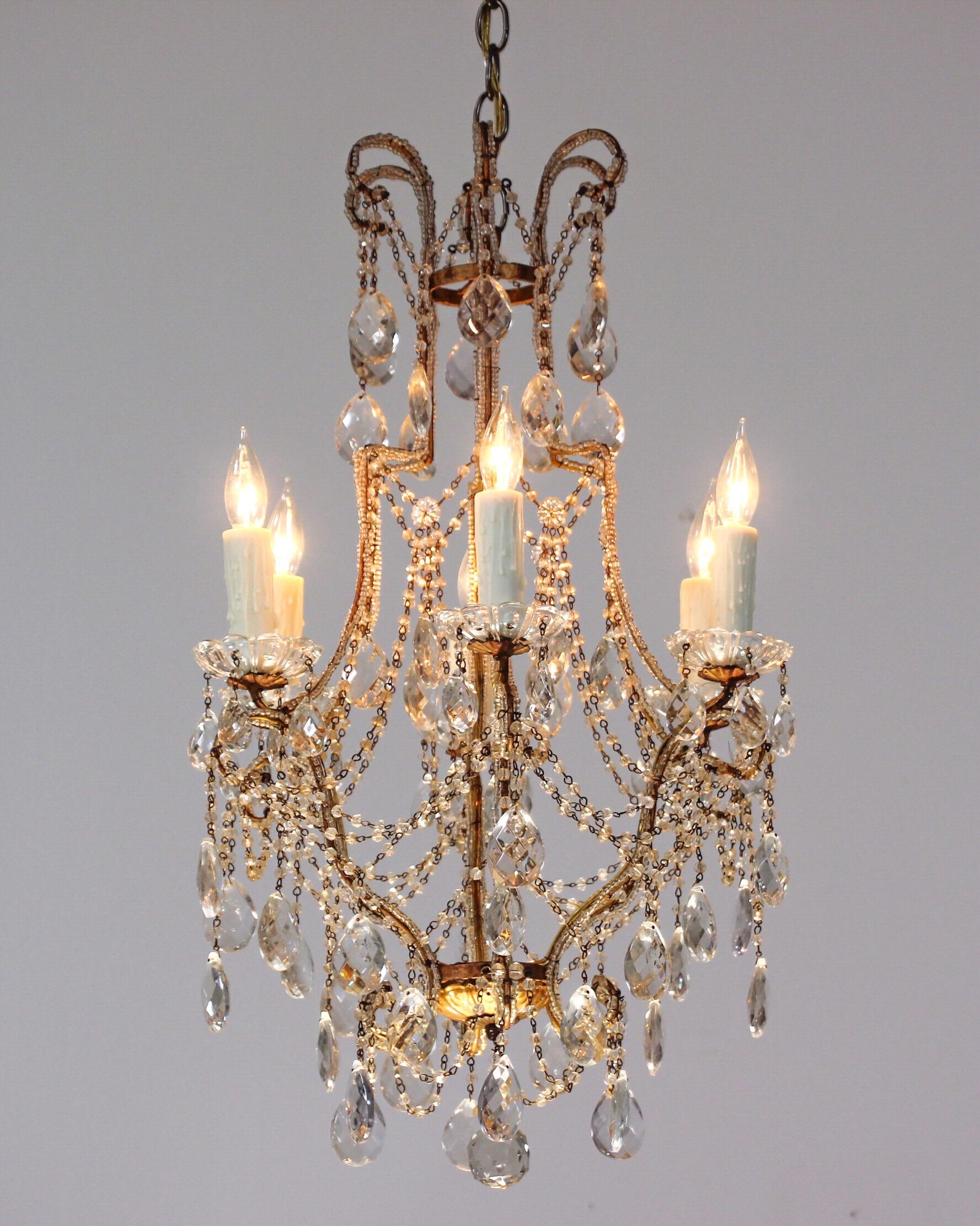      1940s Italian gilt iron chandelier consisting of a crystal beaded gilt-iron frame with faceted prisms and “English cut” bead garlands. 
     Very pretty and delicate in shape, the chandelier would look wonderful in a powder room .
     Wired