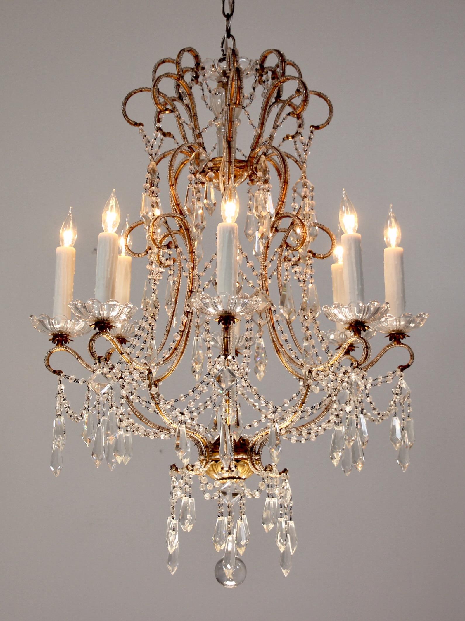 Gorgeous, 1940s Italian beaded chandelier featuring an elegantly scrolled gilt-iron frame which has been hand-beaded throughout its entirety. Note the delicate scalloped bobeches, bead garlands and sparkling crystal prisms.

This graceful chandelier