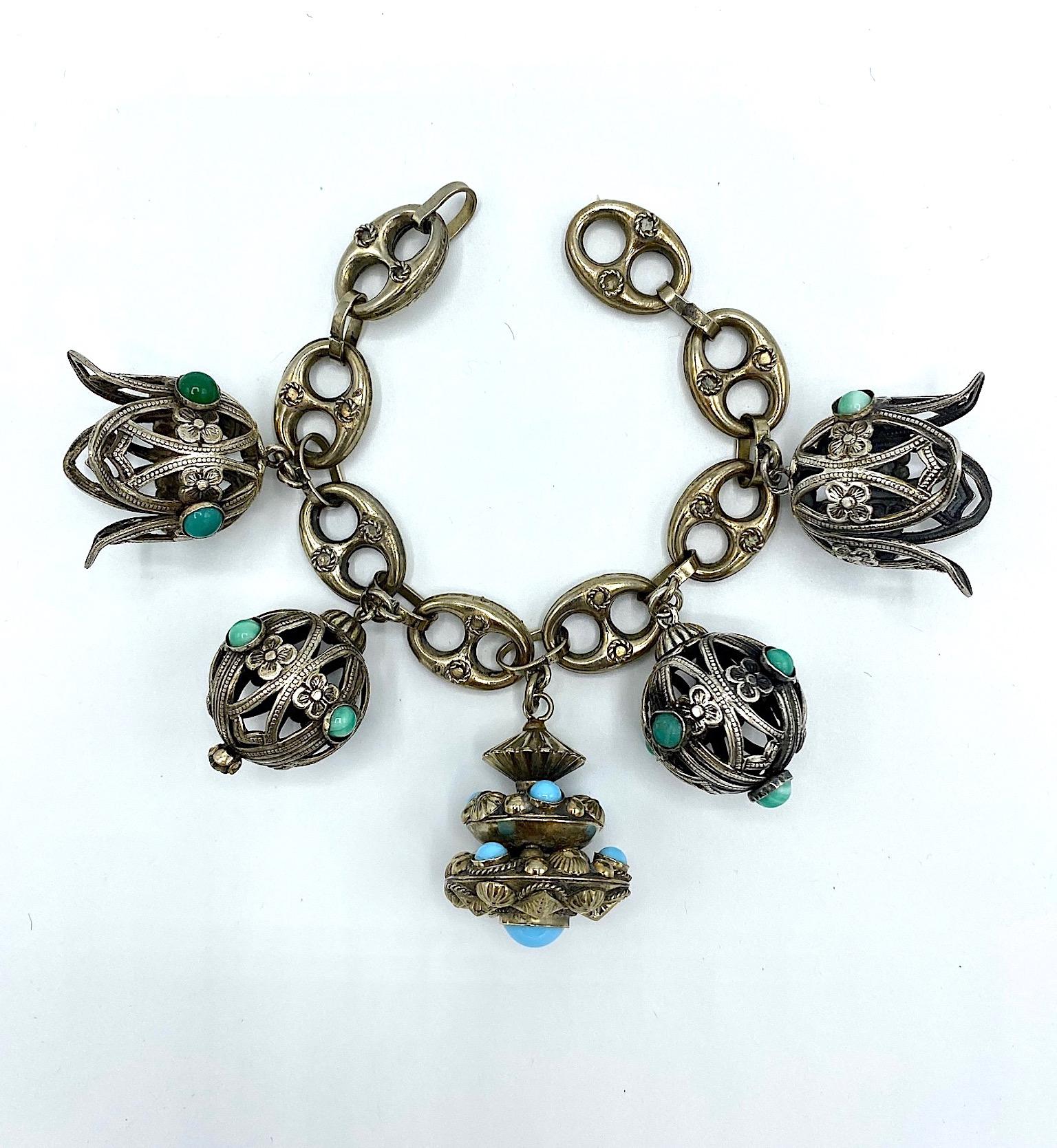 A large and intricately hand made 1940s Italian 800 silver in the Etruscan style. There are four charms in cutwork silver and one large central charm without cutwork. All are set with hand made glass green or blue color cabochons. The bracelet is