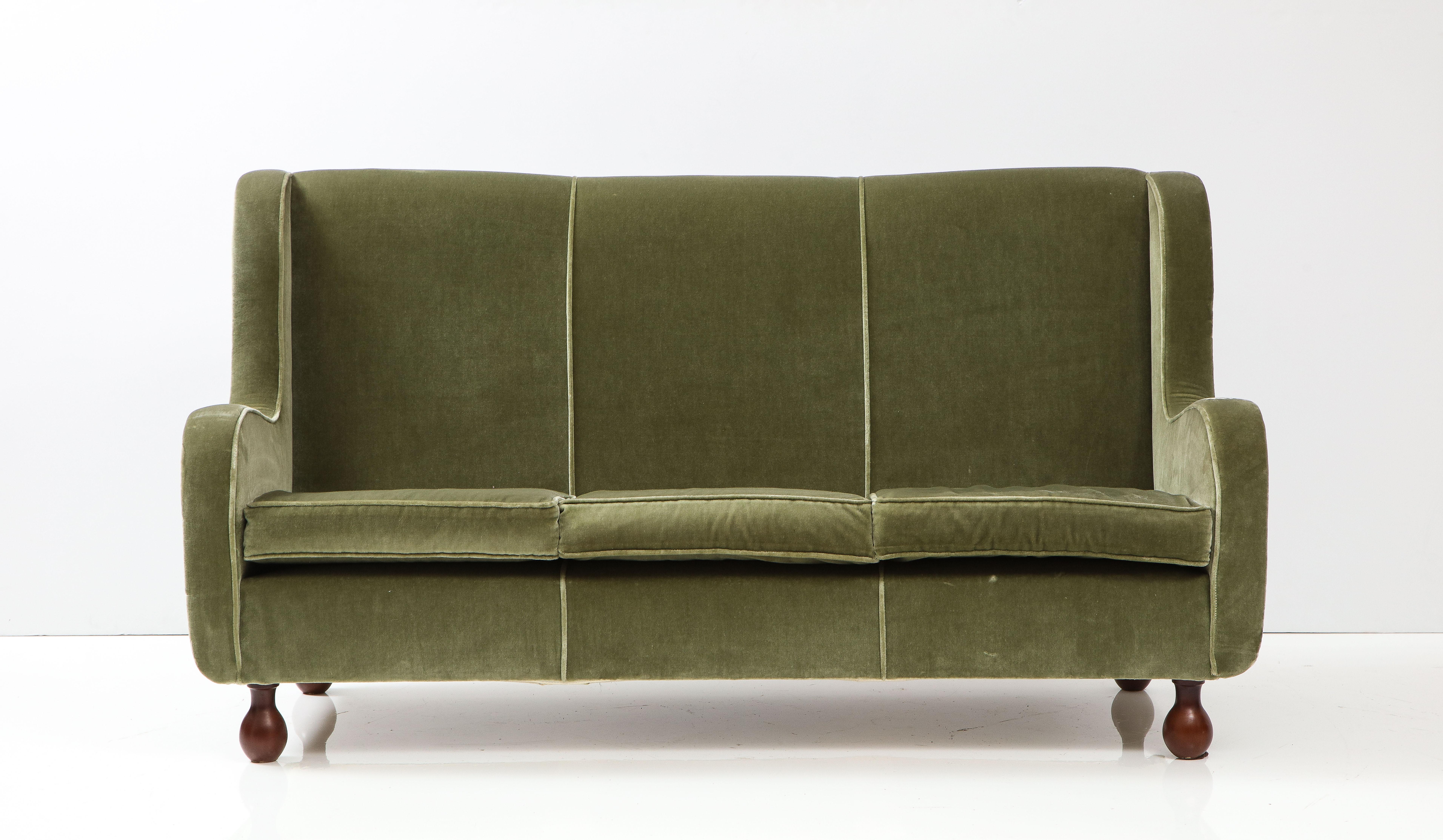 A charming Italian 1940's sofa, upholstered in its original seafoam green velvet, with beautifully curved arms, rectangular back; the whole supported on walnut bun feet. Also available: a pair of slipper chairs and a pair of arm chairs. Inquire